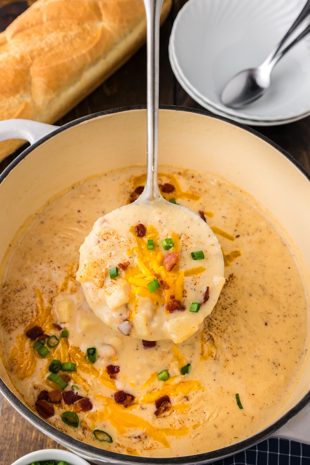 A spoon of soup over a pot of creamy potato soup