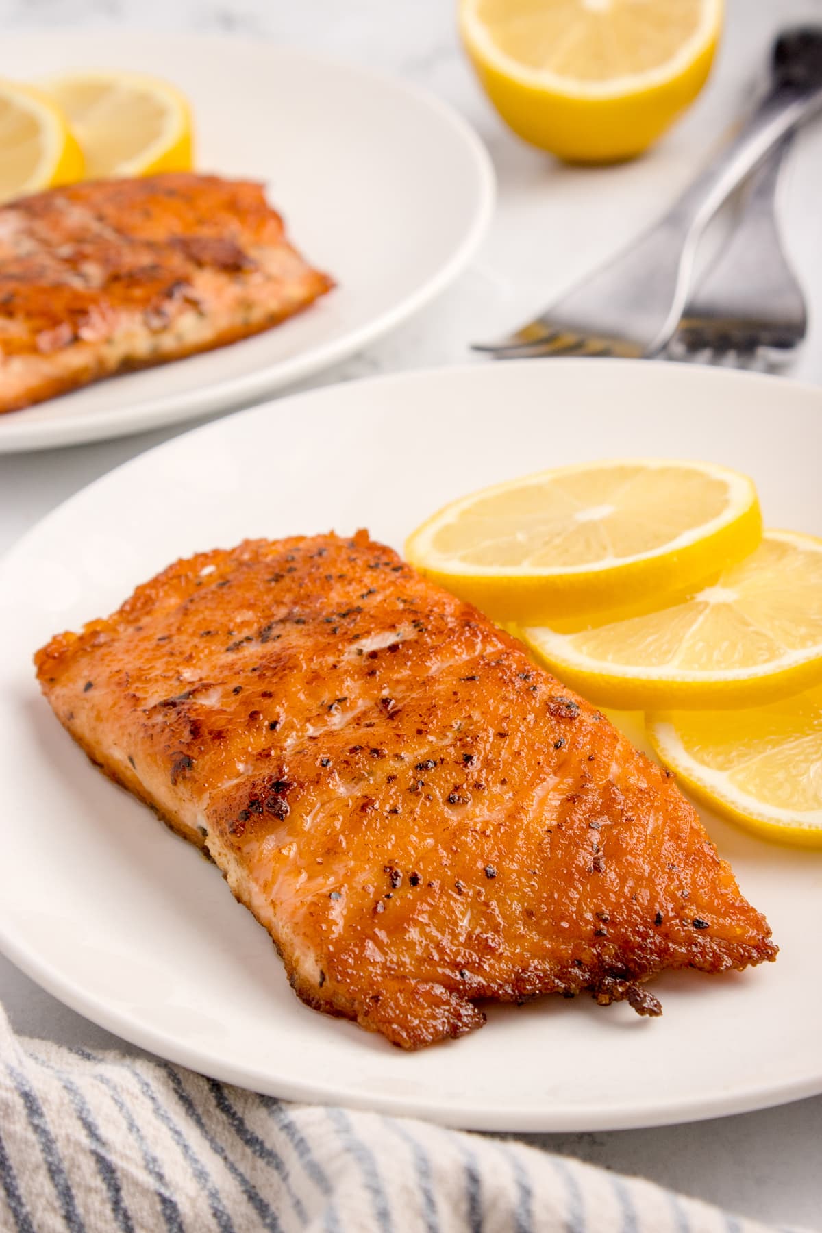 Sous Vide Salmon on white plate with slices of lemon