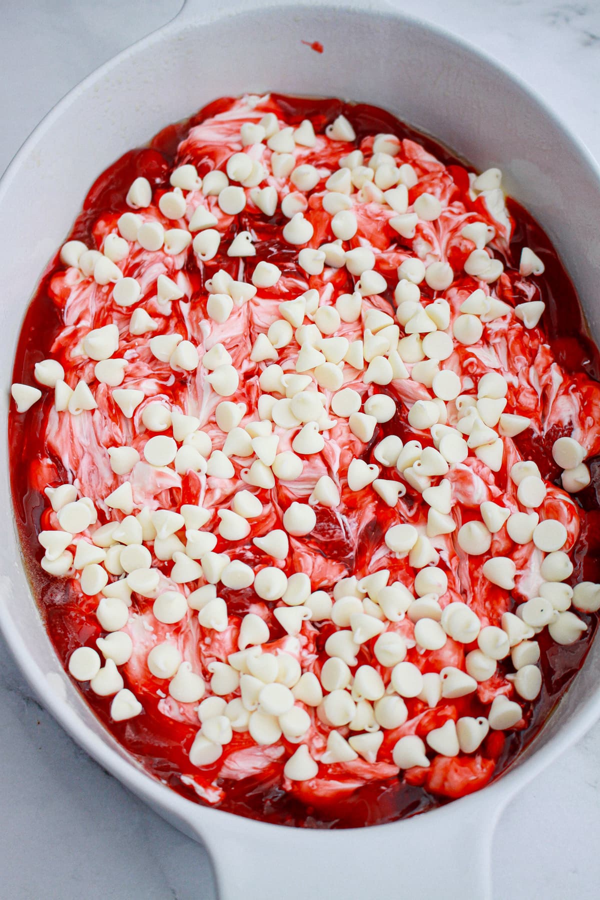 white chocolate chips on top of strawberry pie filling for dump cake
