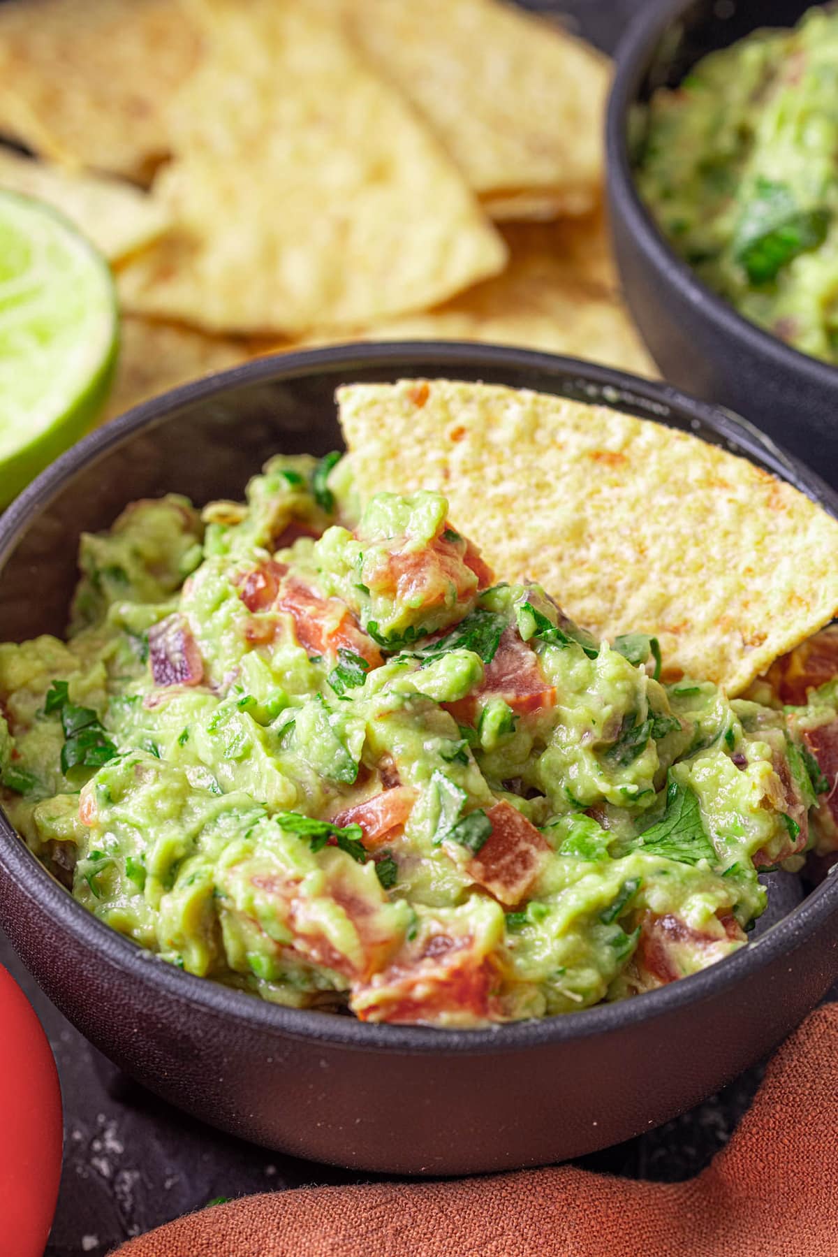 A serving of guacamole dip in a black bowl.