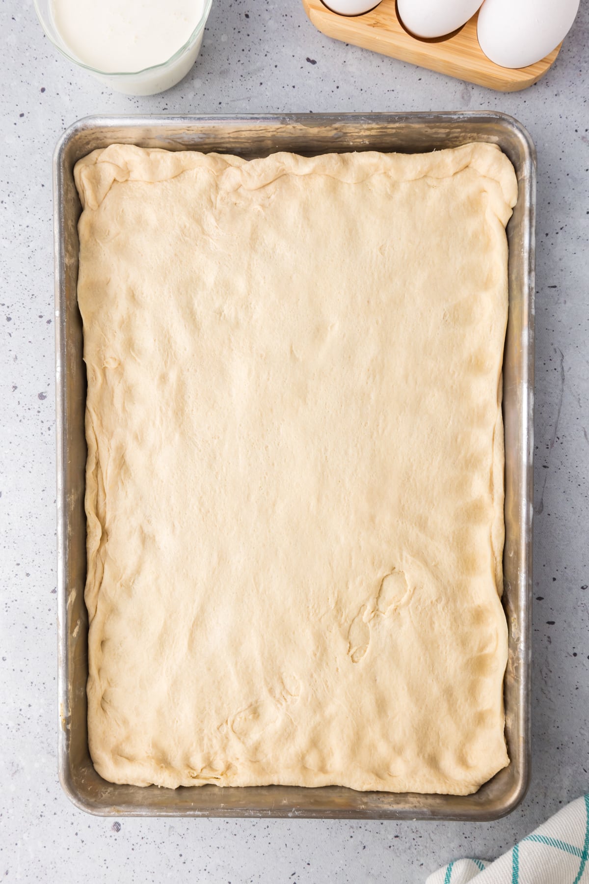 Pizza dough stretched out on a baking sheet.