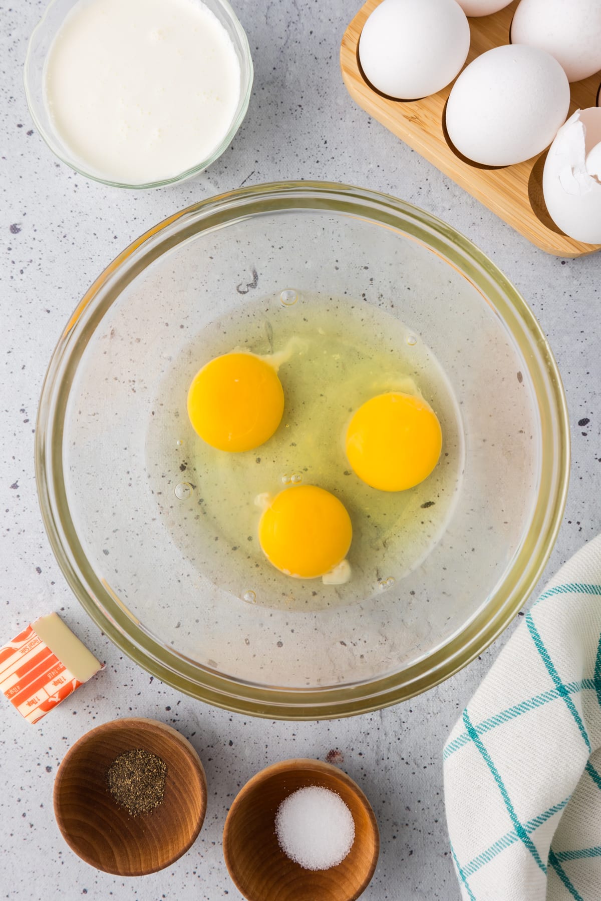 Three eggs cracked into a clear bowl.