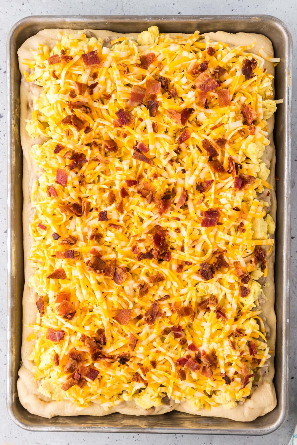 Crispy bacon and shredded cheese topping a breakfast pizza.