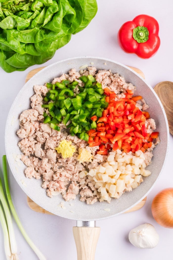 Ground chicken, red and green bell peppers, and onion in a skillet