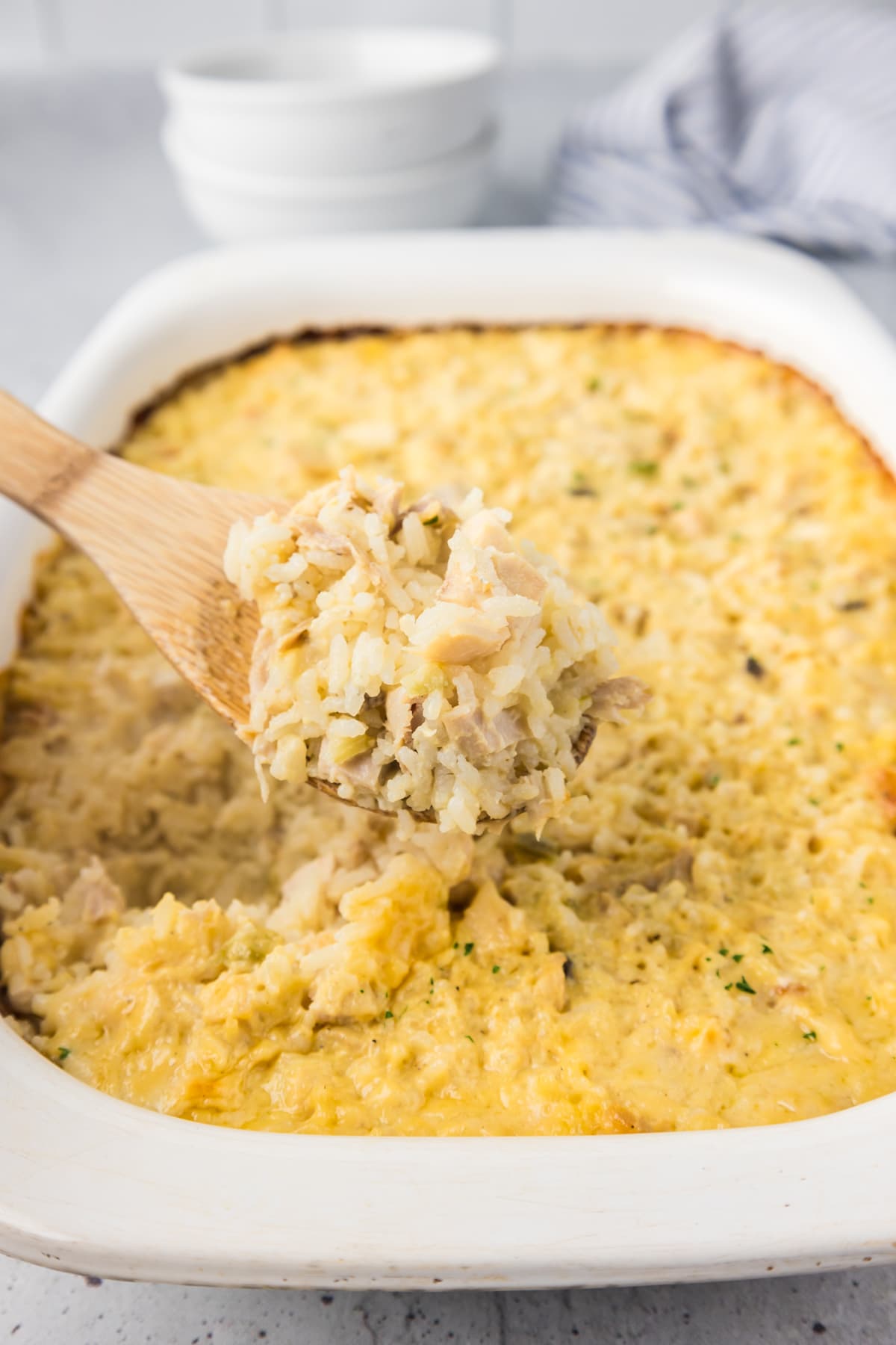 chicken and rice casserole in white baking dish with wooden spoon