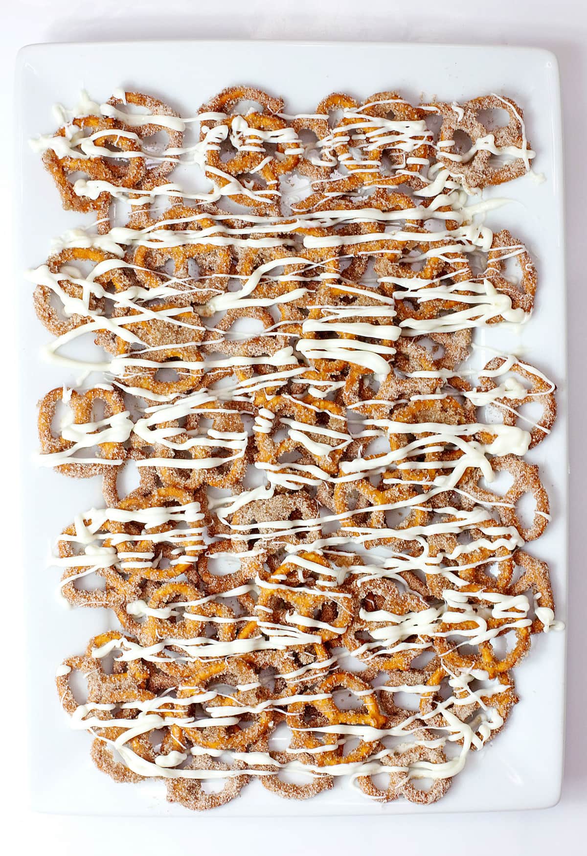 Cinnamon Sugar Pretzels on a white tray drizzled with chocolate.