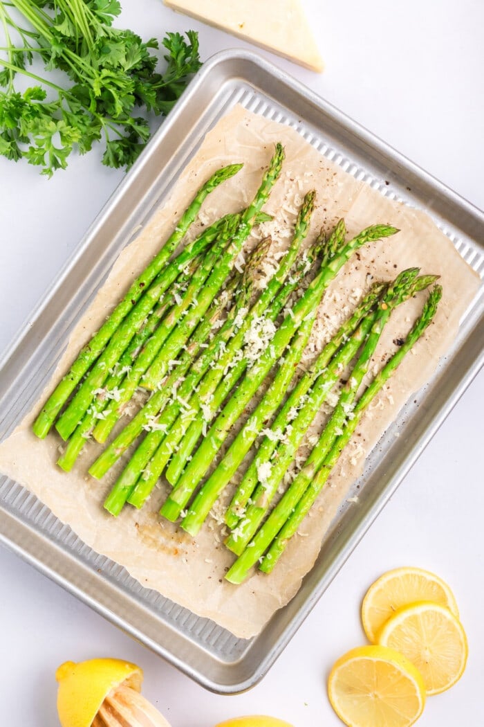 Asparagus topped with parmesan on a baking sheet