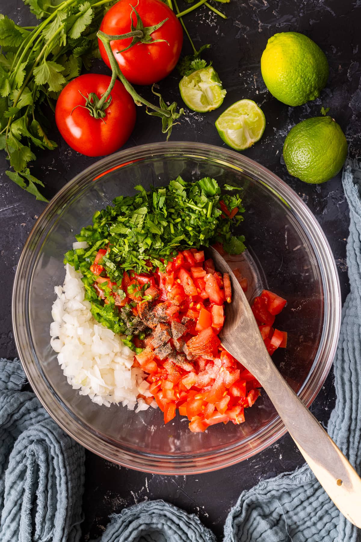 chopped tomatoes, cilantro, spices, lime  and onion in a glass bowl. 