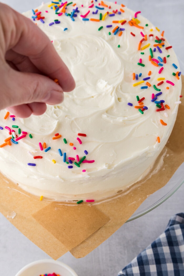 Sprinkles being added to buttercream on a cake