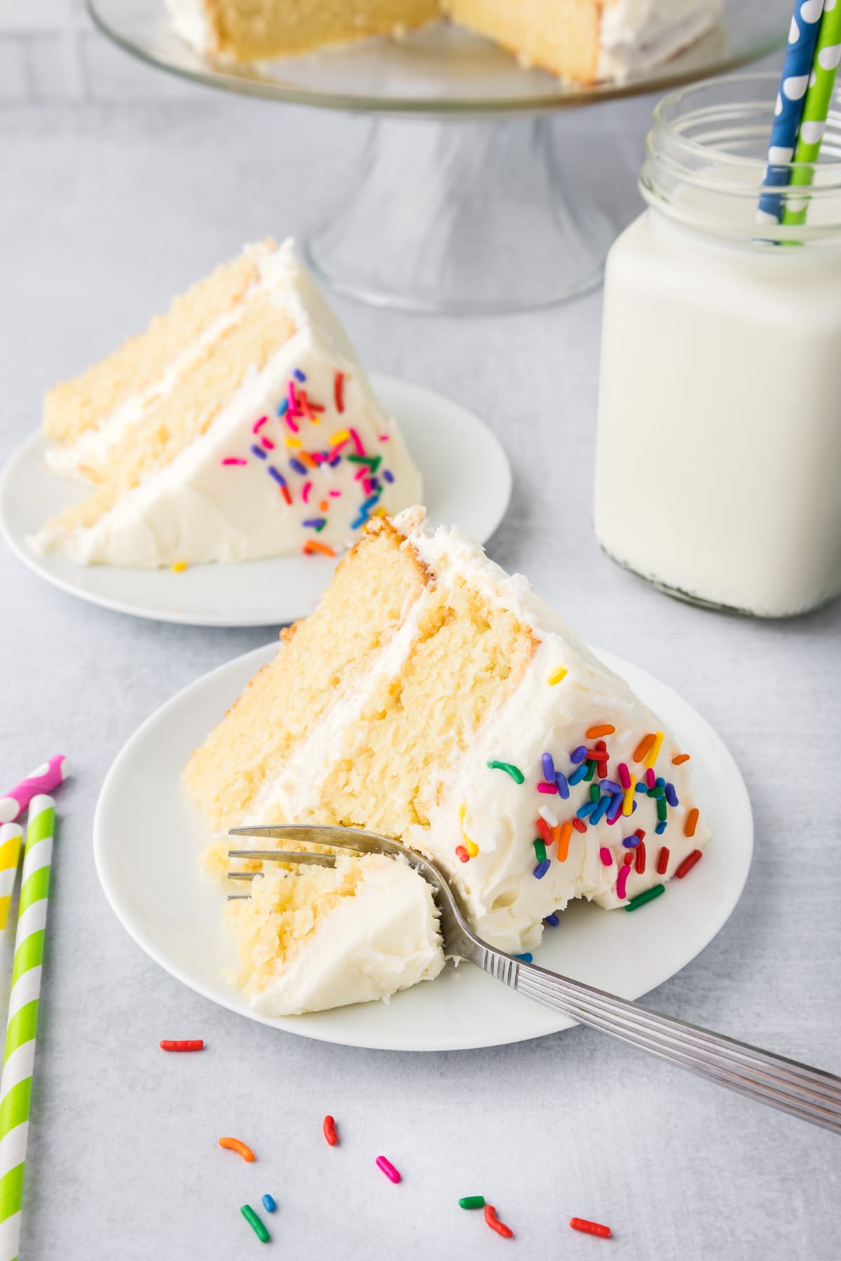 A fork cutting into a slice of vanilla cake