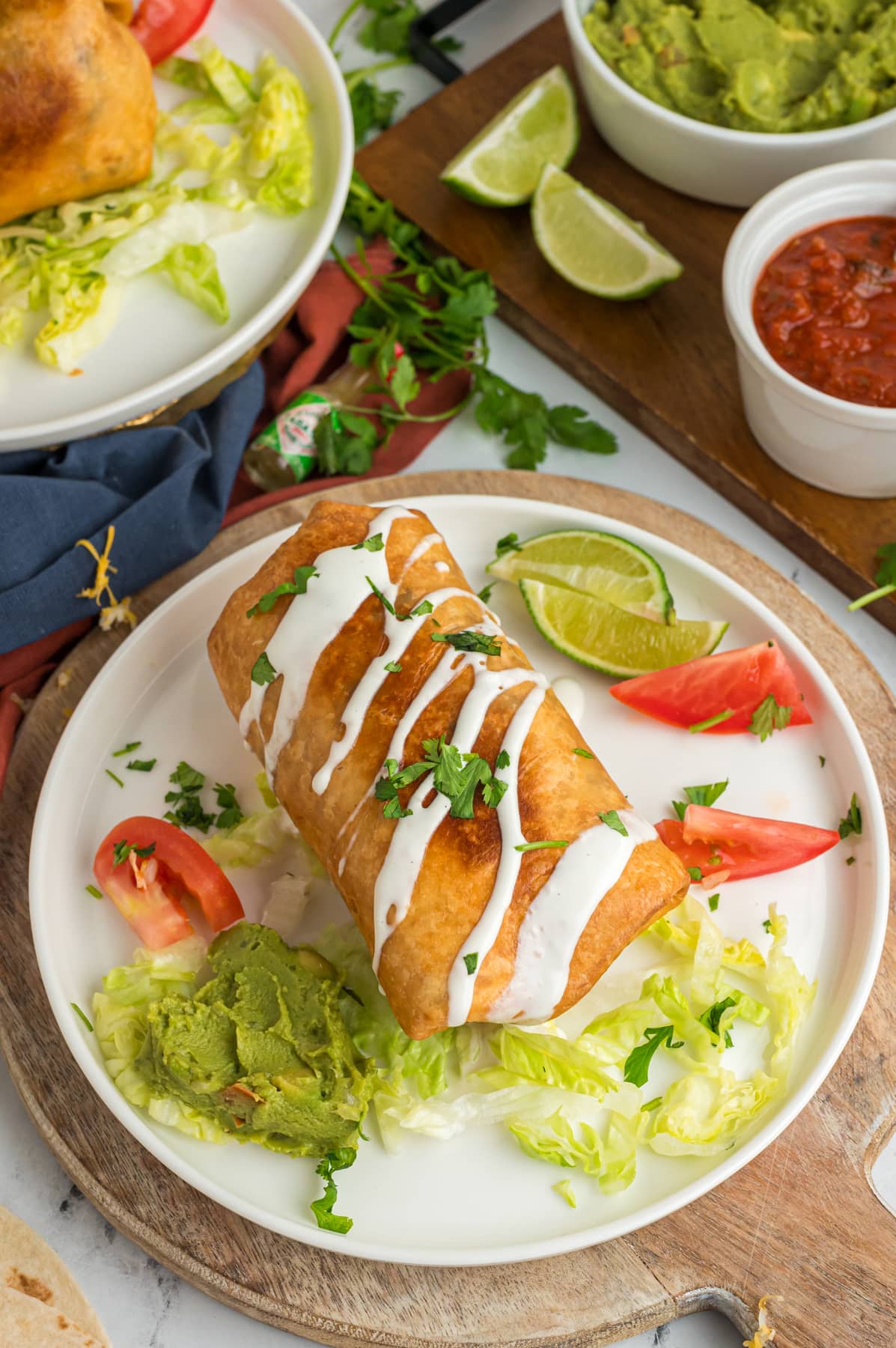 Chicken Chimichanga on plate with limes, lettuce and tomatoes