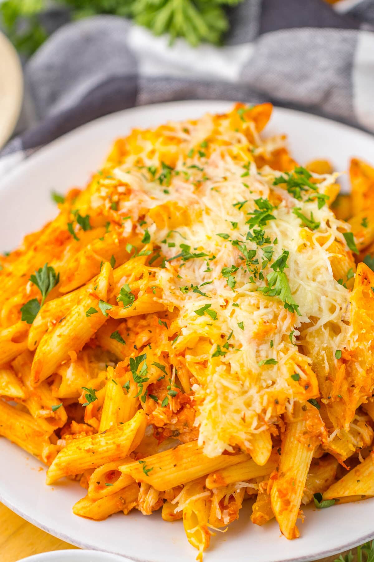 This Chicken Parmesan Casserole recipe is the perfect weeknight dinner. It’s made with cooked chicken and prepared pasta sauce to save time but still tastes absolutely delicious. Close up view of Chicken Parmesan Casserole on a white plate.