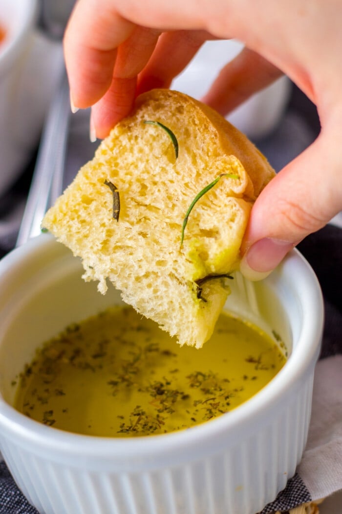 Focaccia bread slice being dipping in herbed olive oil
