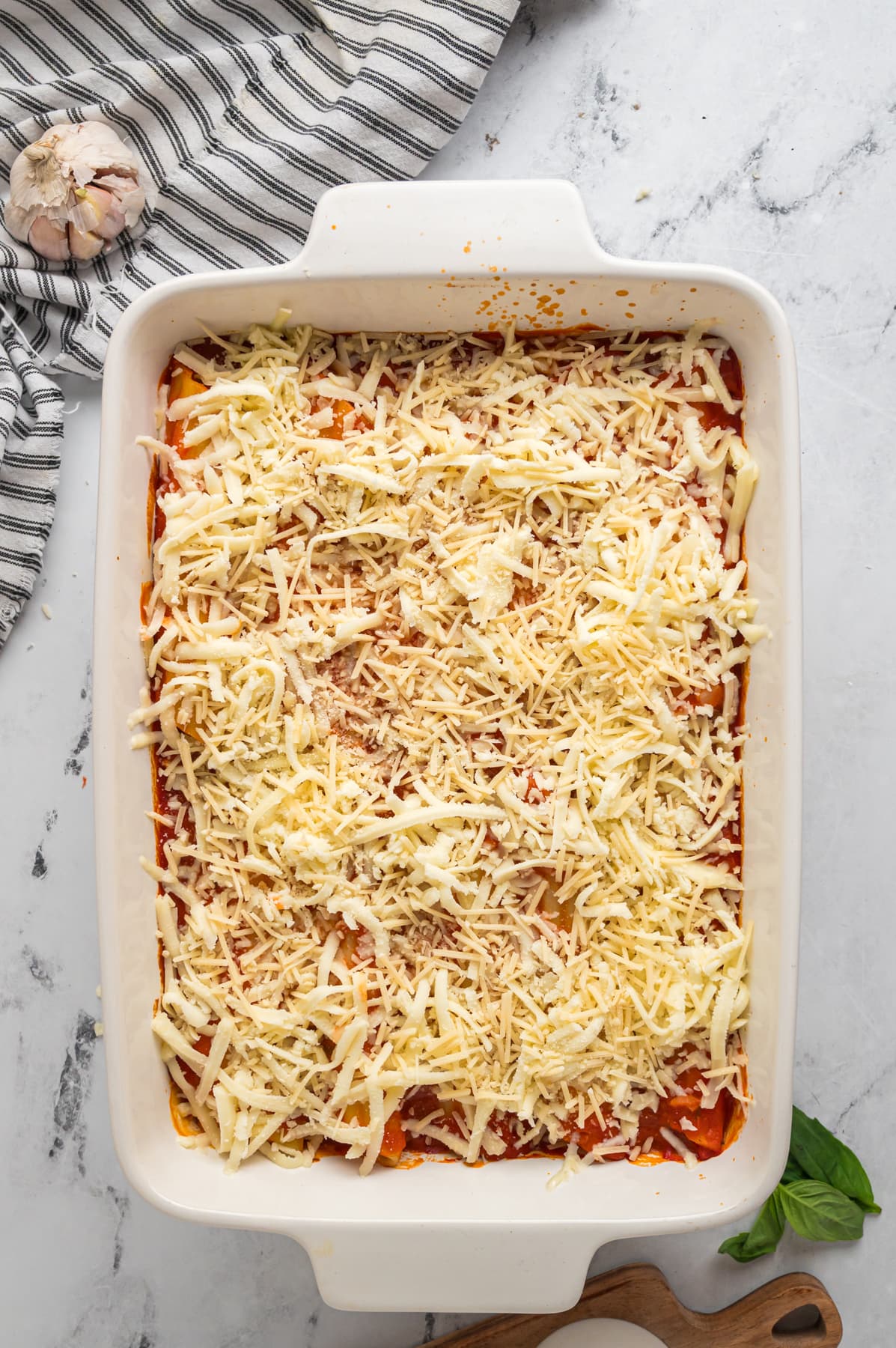 shredded cheese on top of Manicotti in baking dish