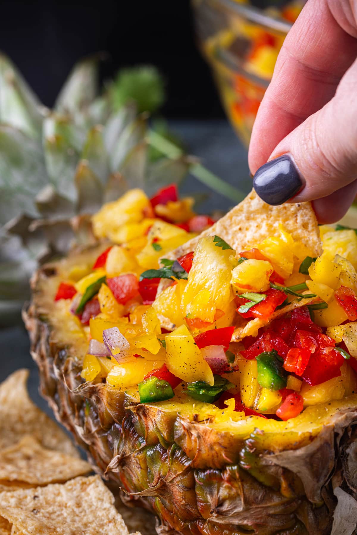 hand dipping chip into Pineapple Salsa
