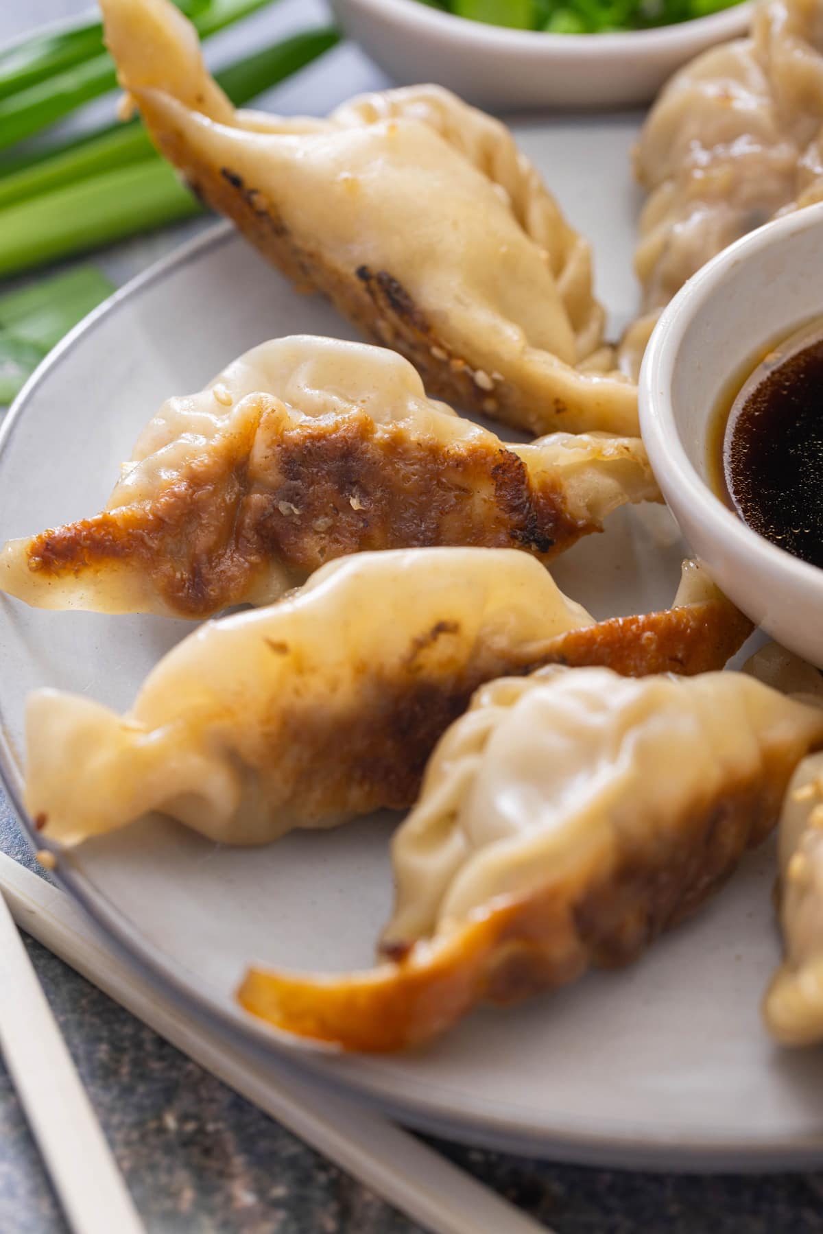 Homemade potstickers on a plate with a bowl of dipping sauce