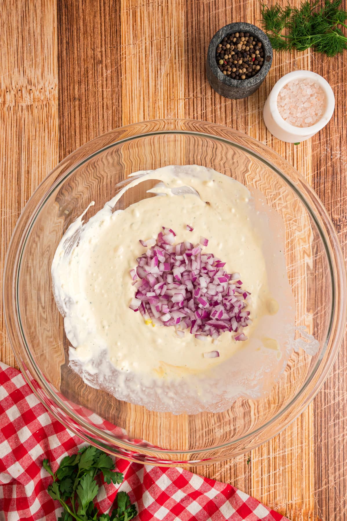 red onion in mixing bowl with dressing for Smashed Potato Salad