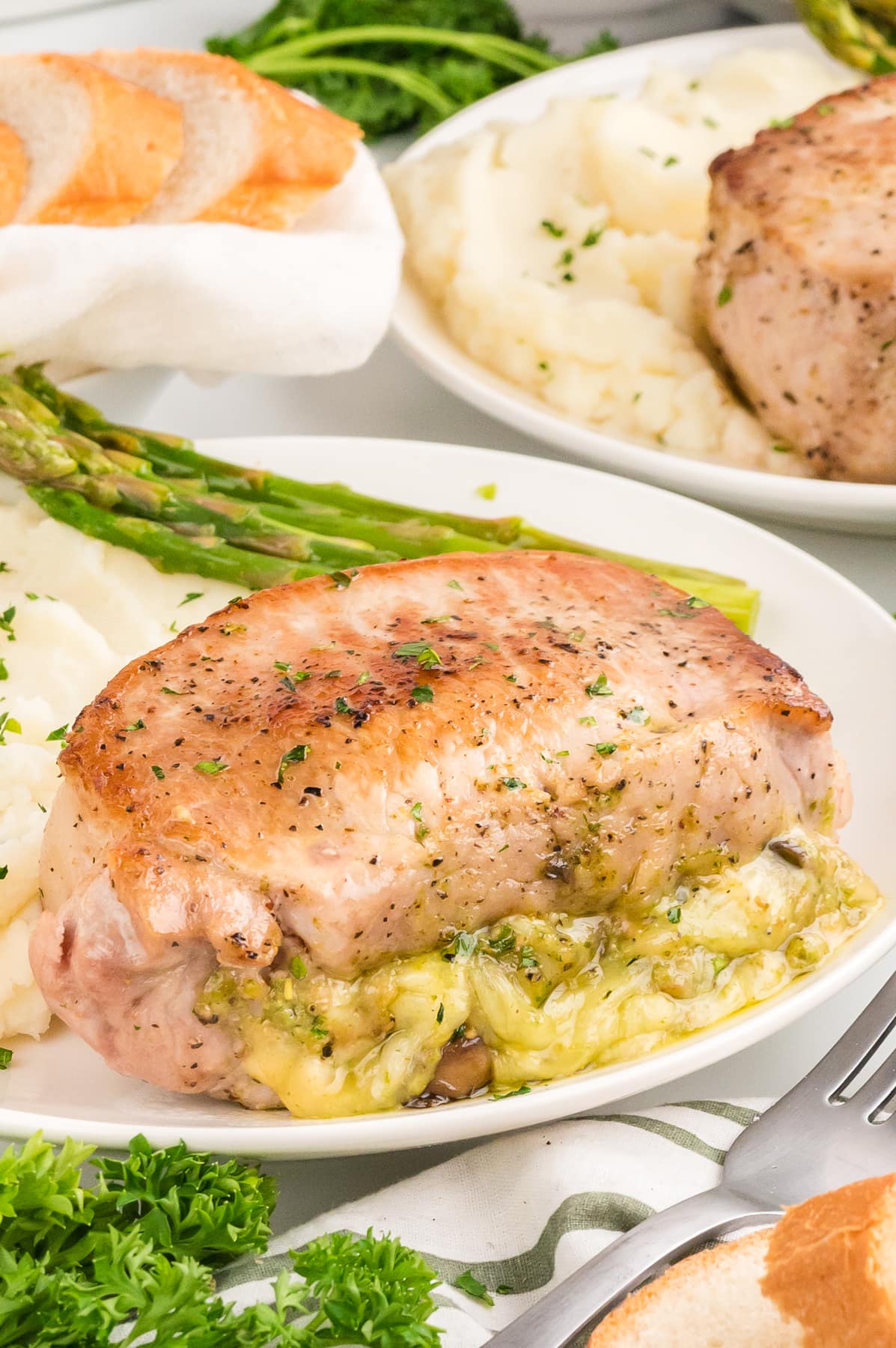 Stuffed Pork Chops on white plate with potatoes and asparagus