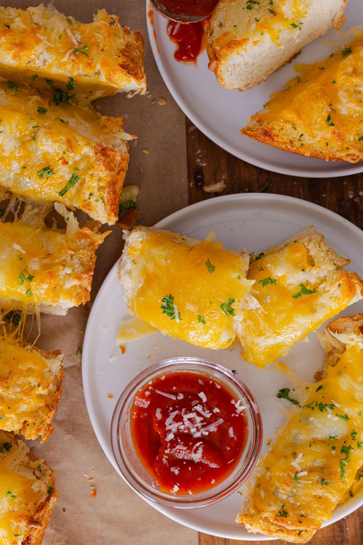 Overhead view of garlic bread with cheese on a plate with marinara sauce