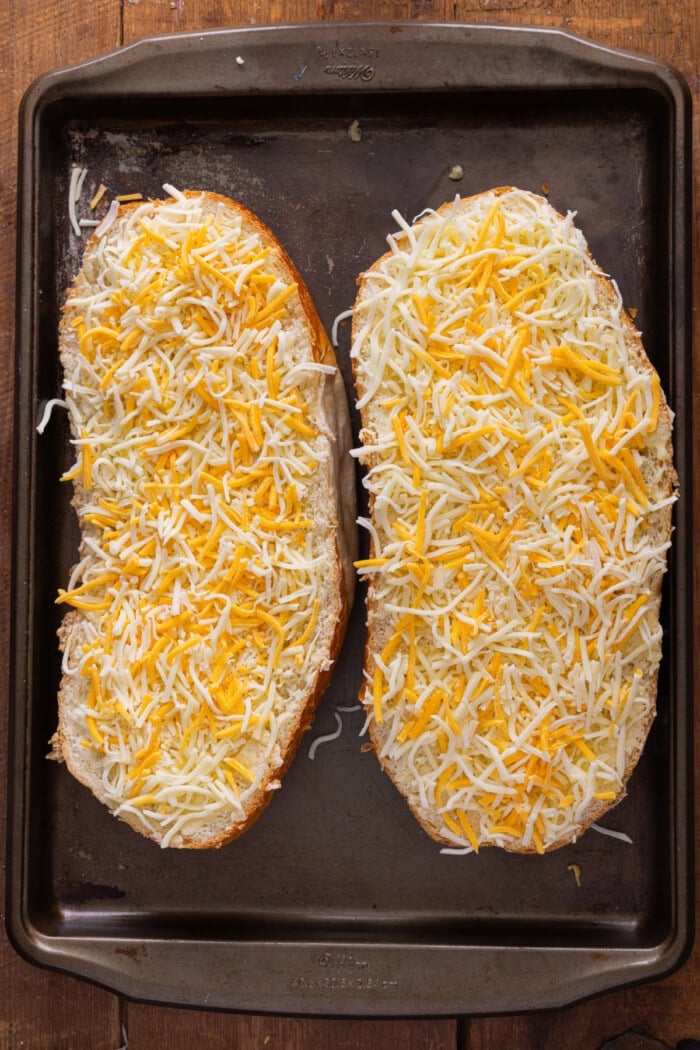 Two halves of French bread topped with shredded cheese