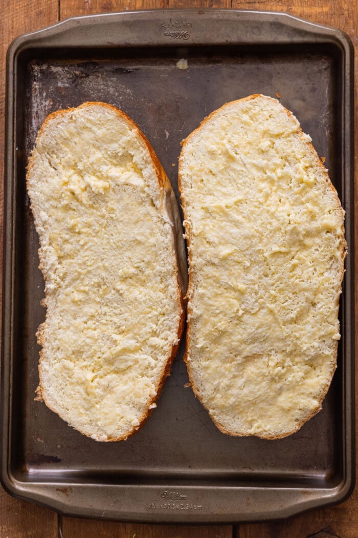 Two halves of French bread slathered with garlic butter