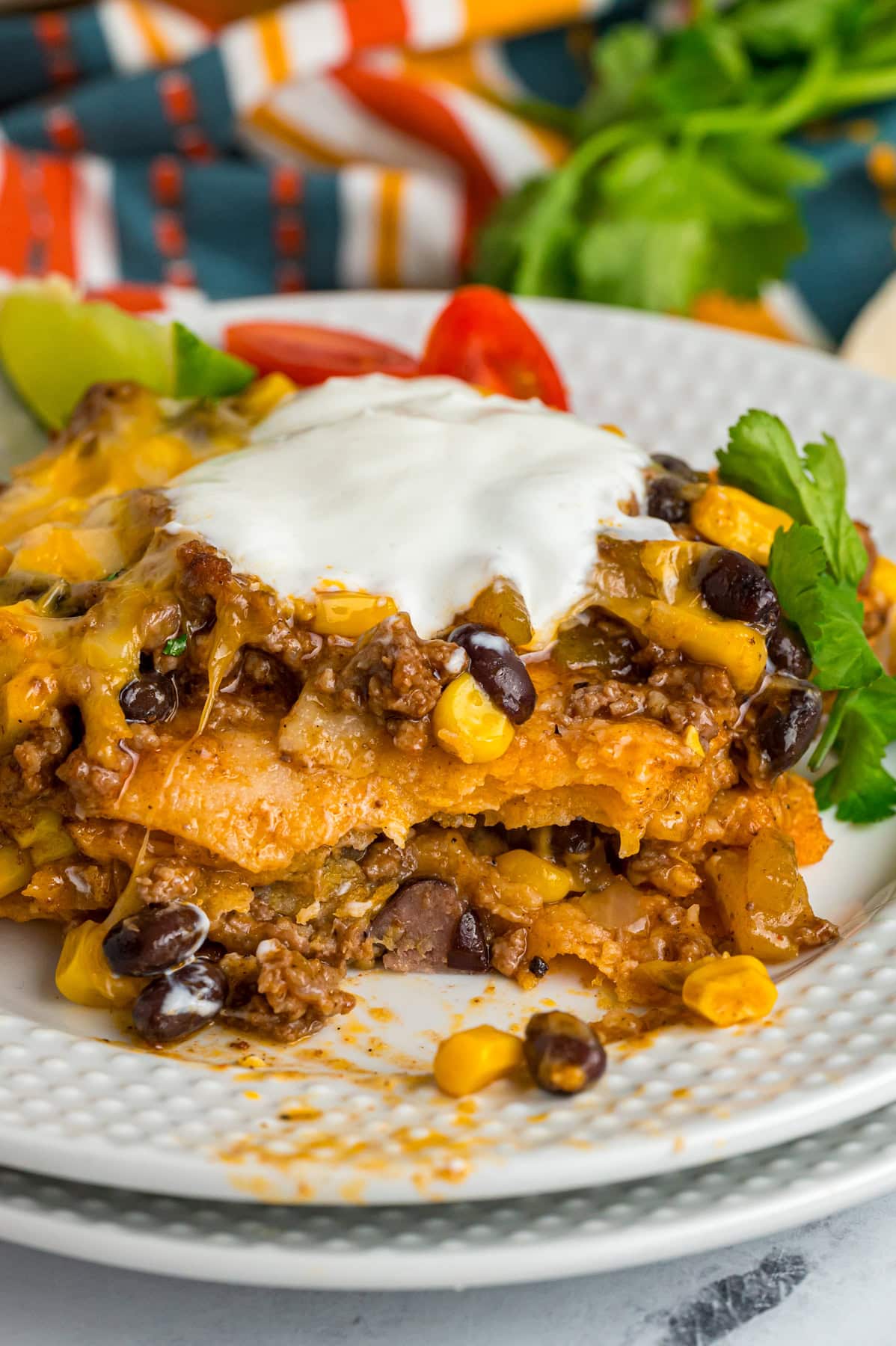 Beef enchilada casserole on a plate with sour cream
