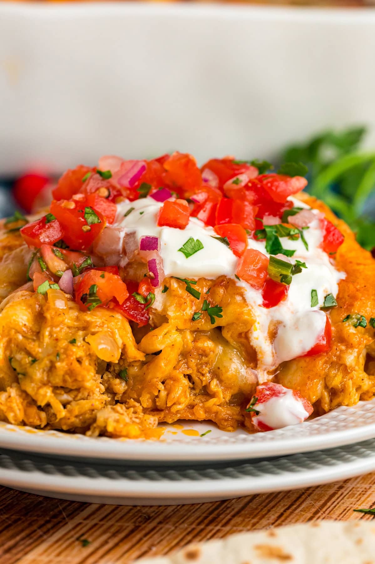 A plate of chicken enchiladas topped with sour cream and tomatoes