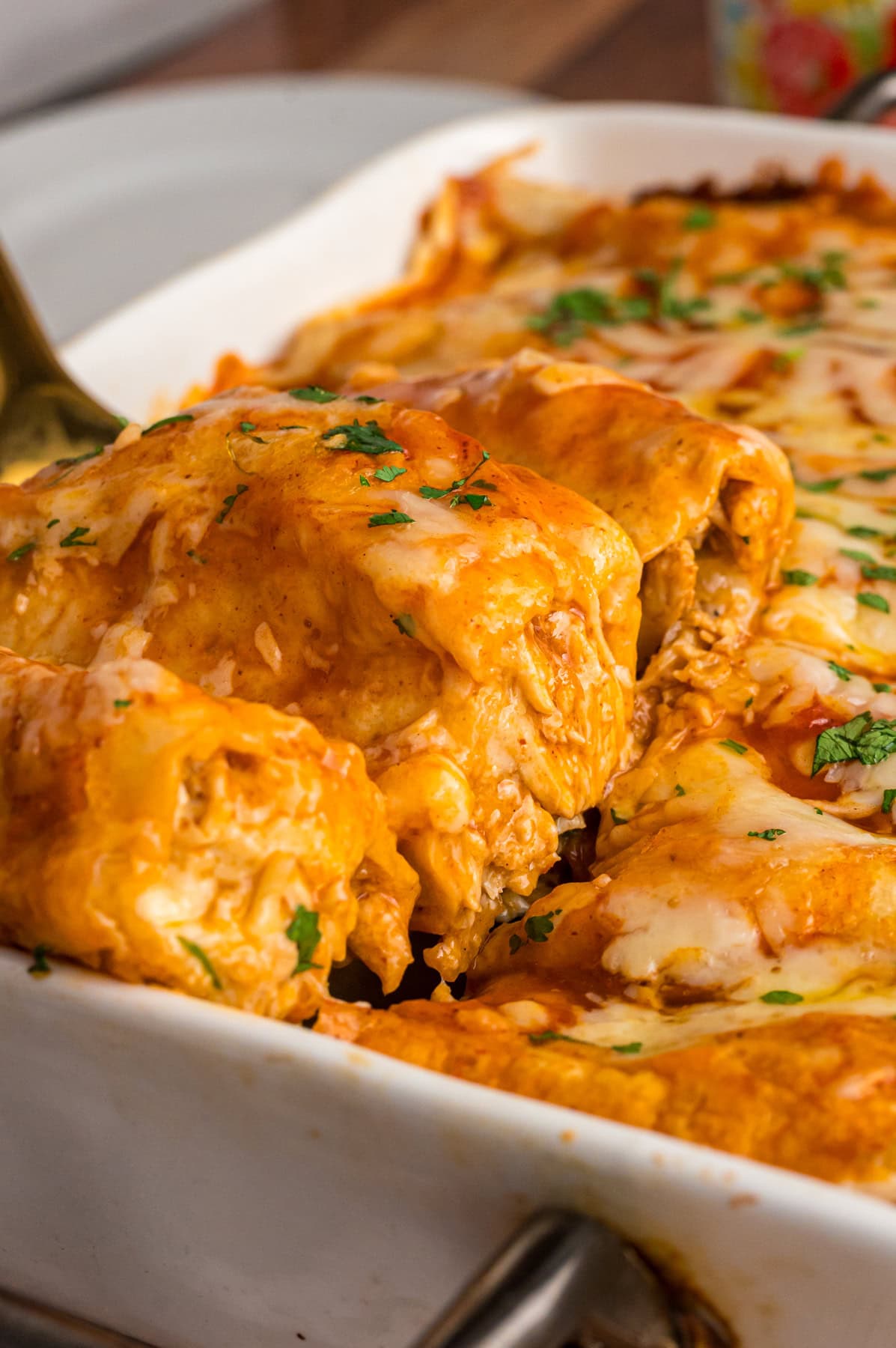 A spatula serving red chicken enchiladas