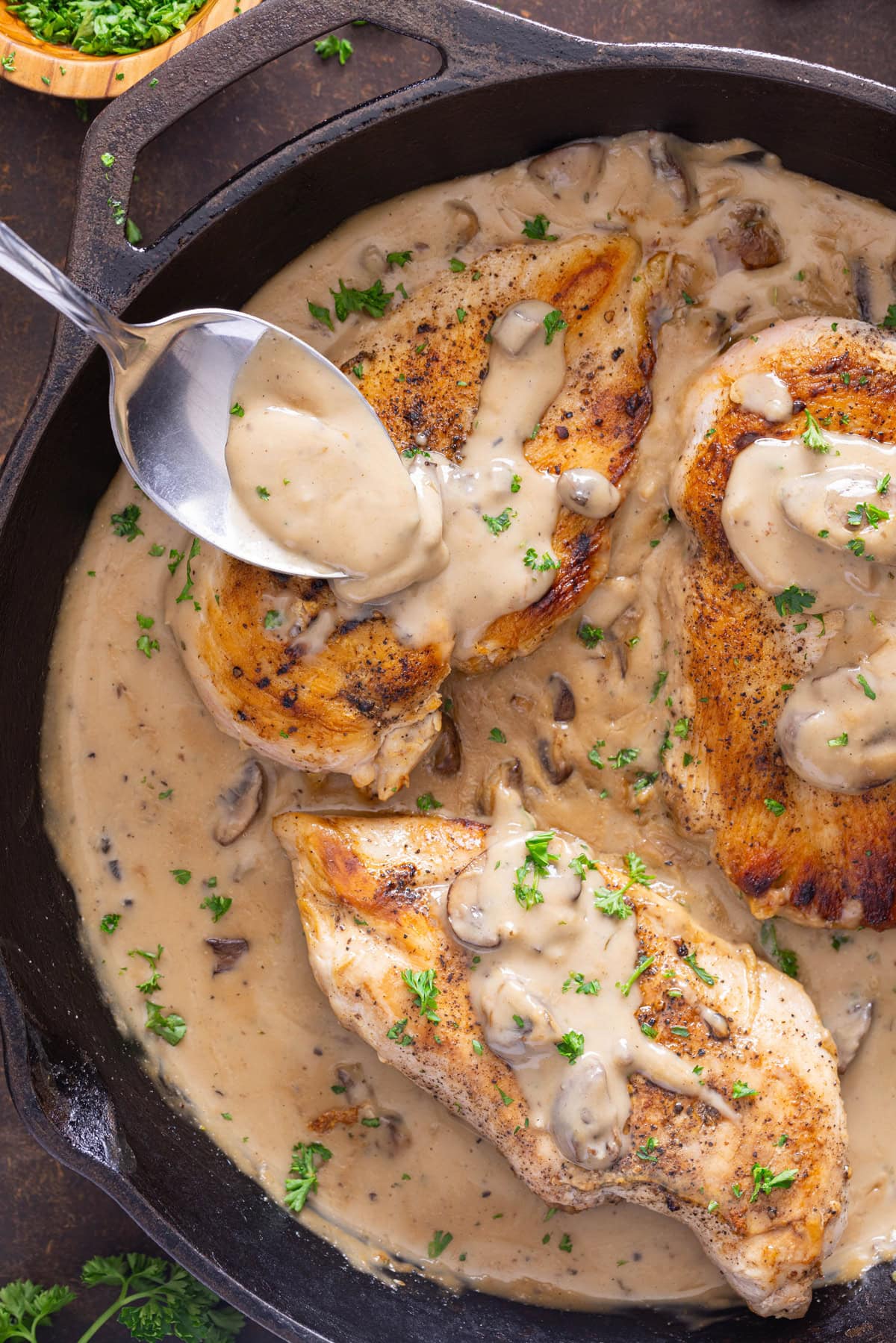 Cream of Mushroom Chicken in cast iron skillet with sauce spooned over