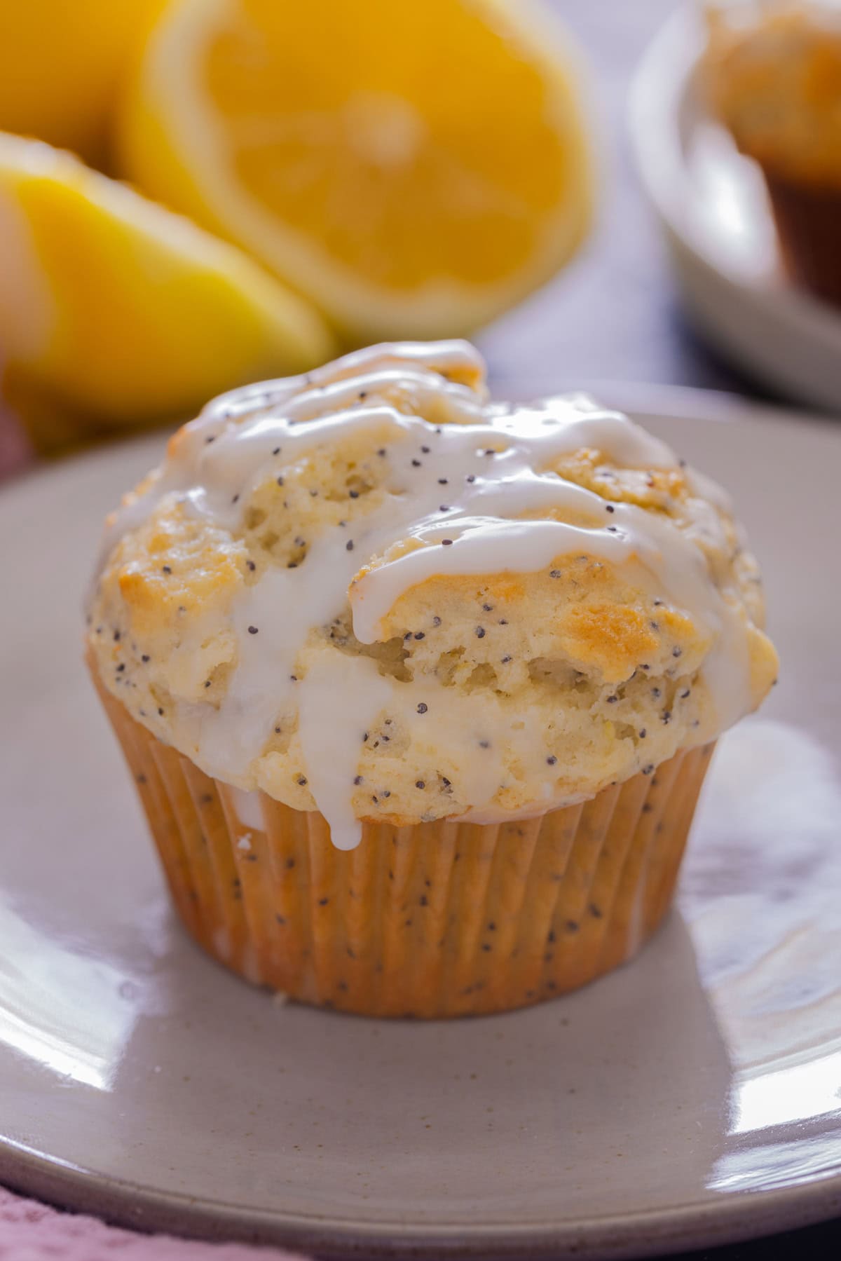 These moist Lemon Poppy seed Muffins are bursting with fresh lemon flavor! They are perfect for breakfast or to enjoy as a sweet snack. A Lemon Poppyseed Muffin on a white platw.