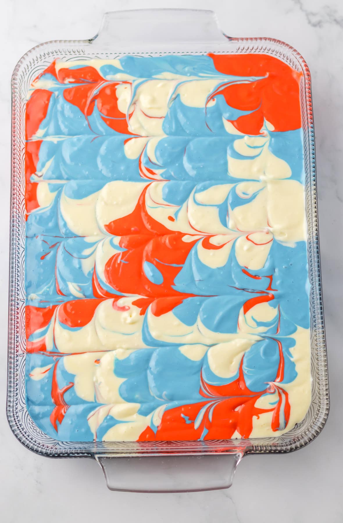 Red White and Blue Cheesecake Batter swirled together in a baking dish.