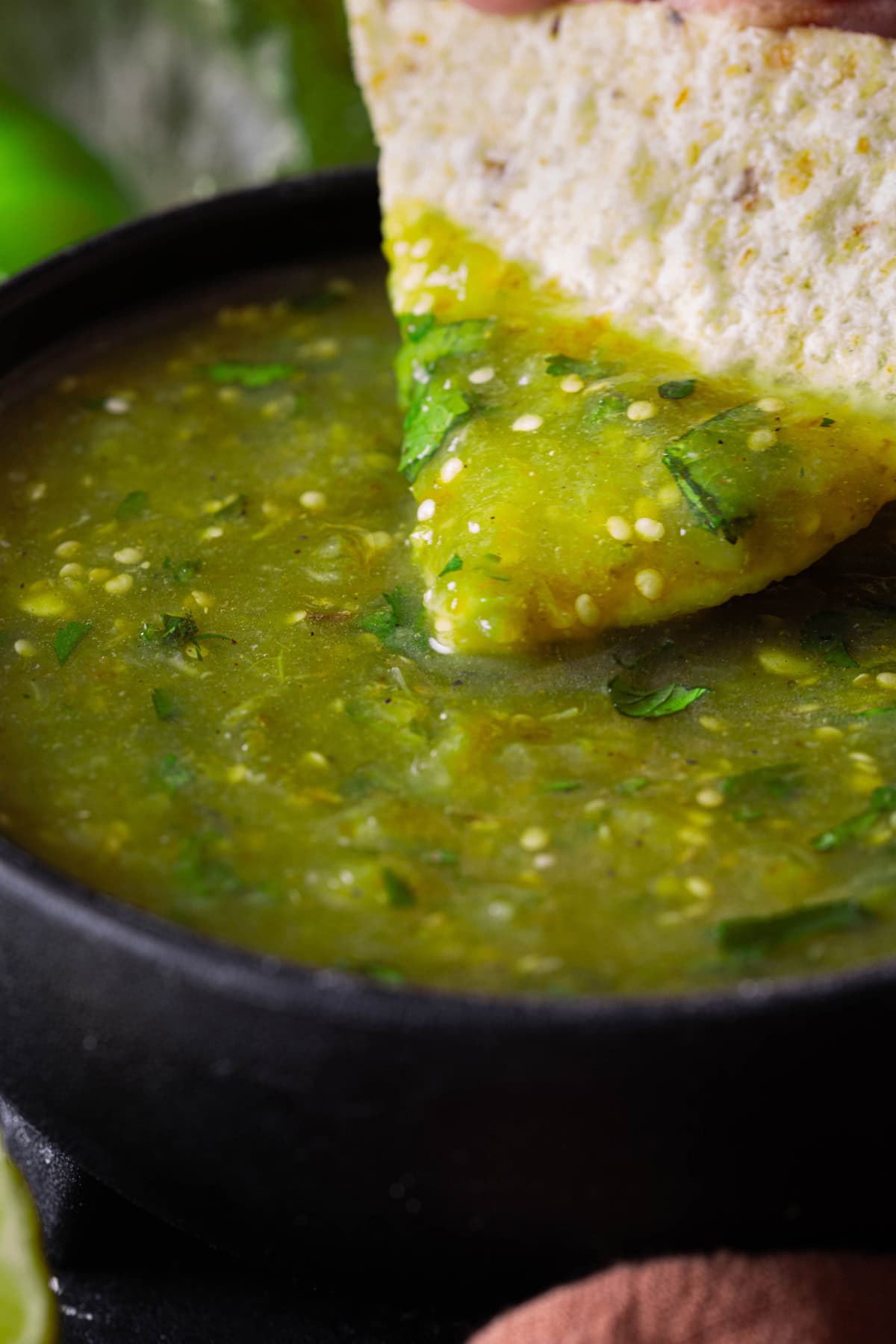 Salsa verde in a black bowl with a tortilla chip