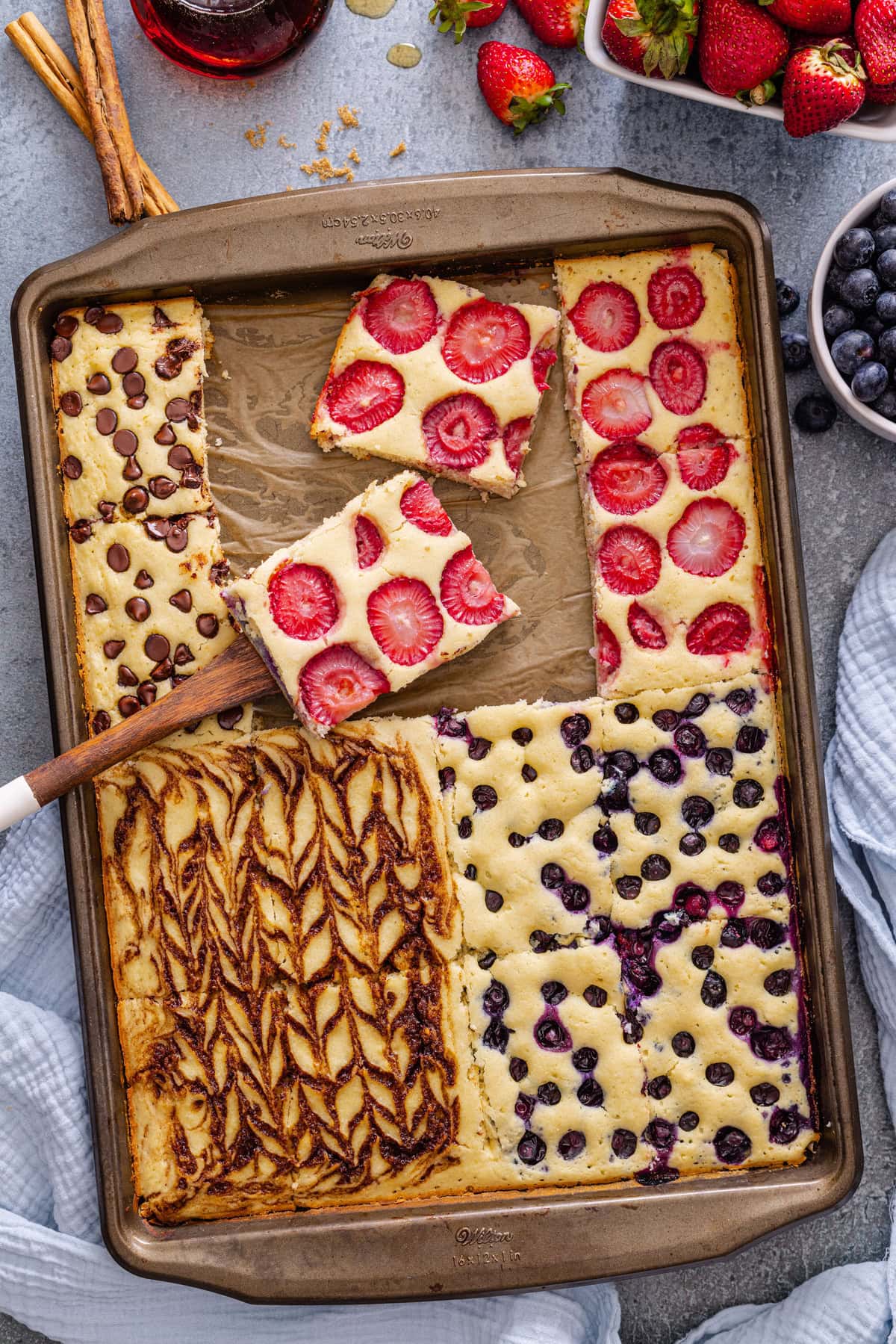 These Sheet Pan Pancakes are a quick and easy way to make tasty, fluffy pancakes in the oven! It’s the perfect recipe to feed a crowd or to make for a delicious weekend brunch. Four flavors of Sheet Pan Pancakes baked on a baking sheet.