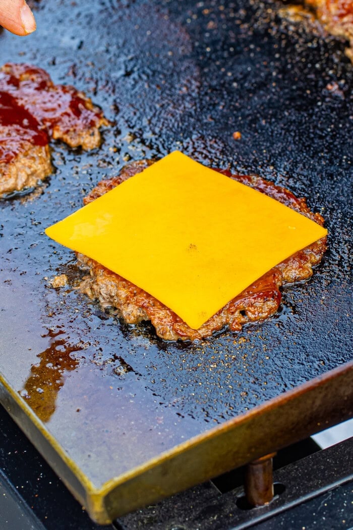 A slice of cheddar cheese on a burger patty