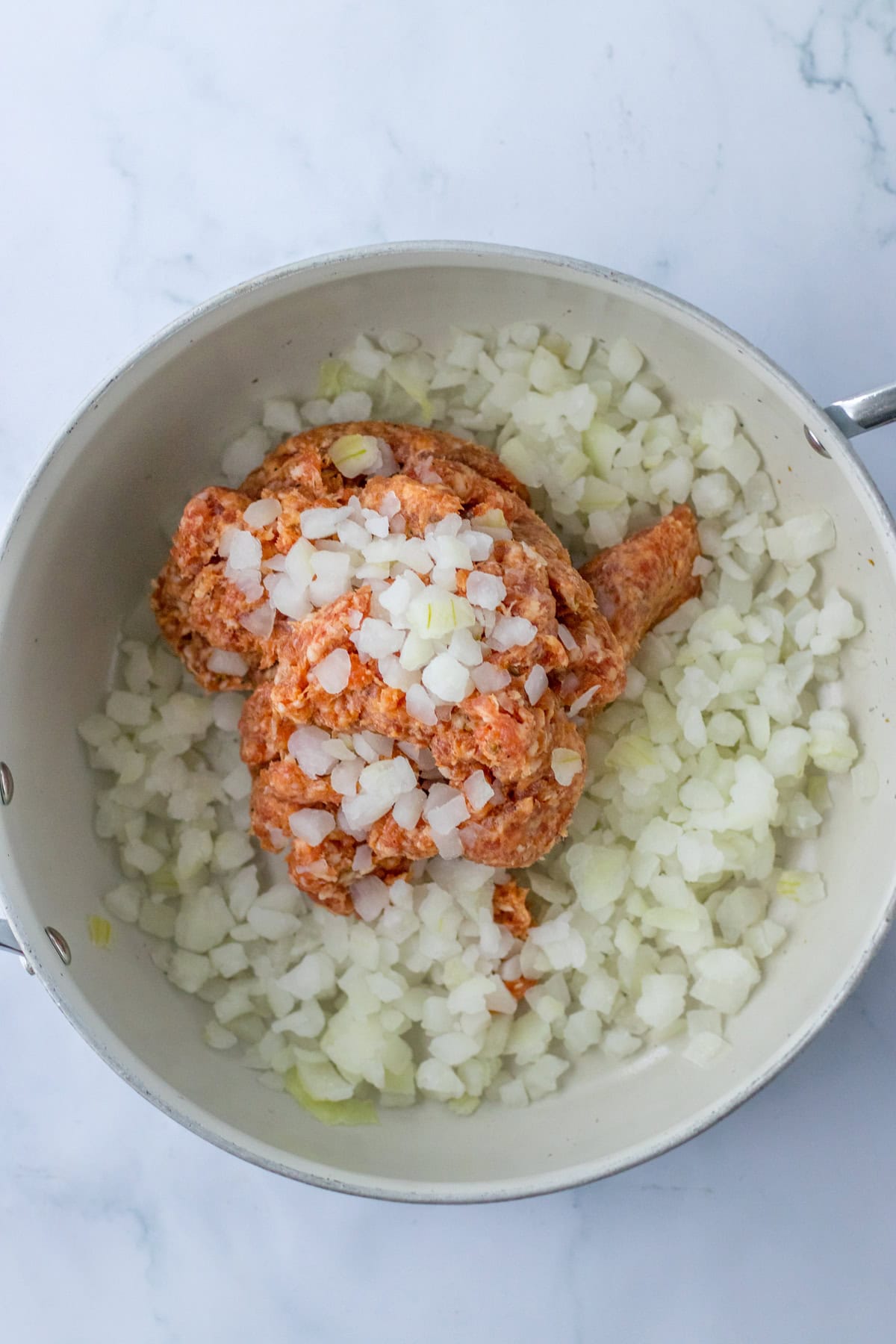 This savory and flavorful recipe for Crockpot Tortellini Soup is great any night of the week. It’s a comforting meal that even tastes delicious for lunch the next day. Italian Sausage and onions in a light colored skillet.