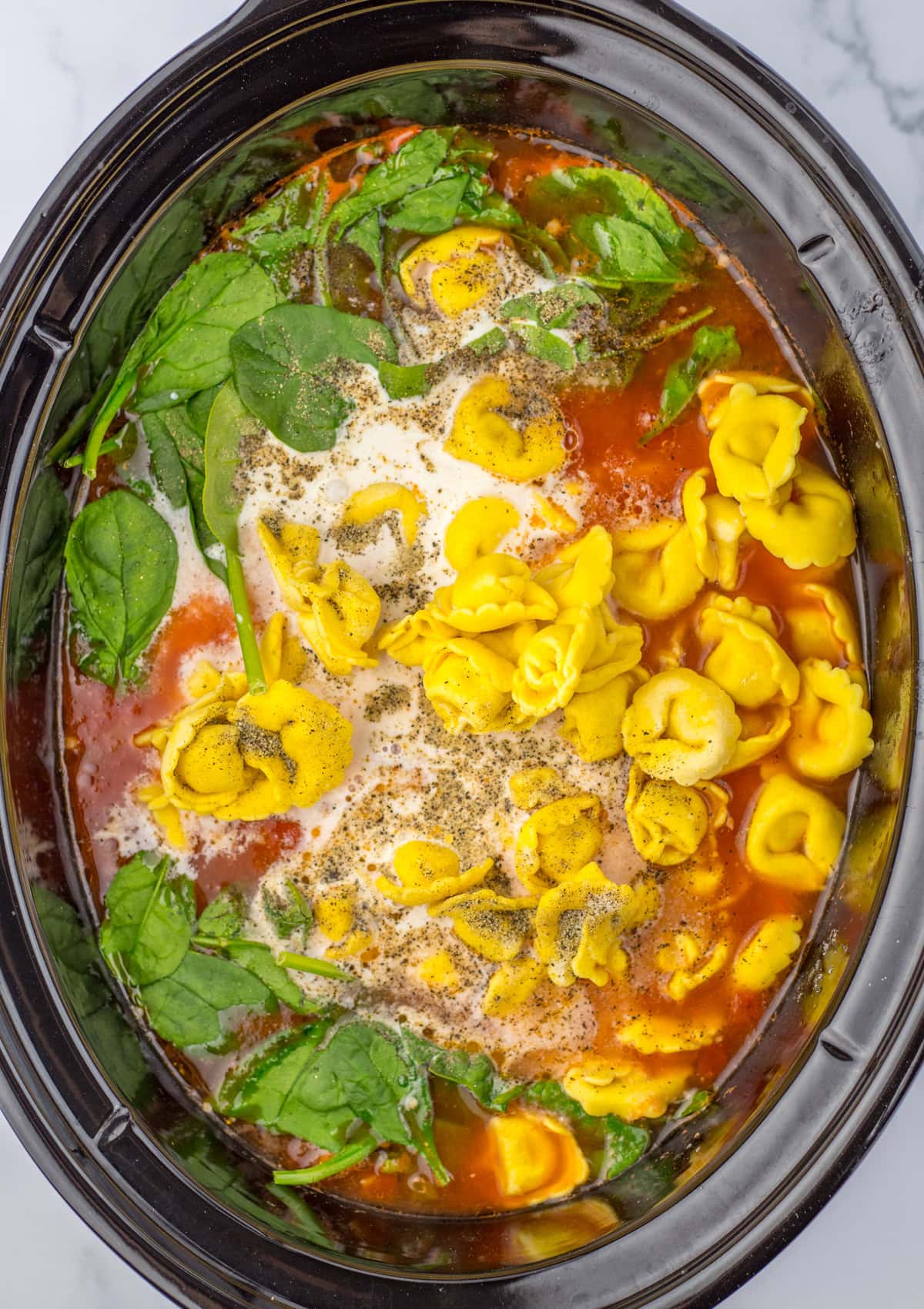 This savory and flavorful recipe for Crockpot Tortellini Soup is great any night of the week. It’s a comforting meal that even tastes delicious for lunch the next day. Spinach, tortellini added to the broth to make Crockpot Tortellini Soup.