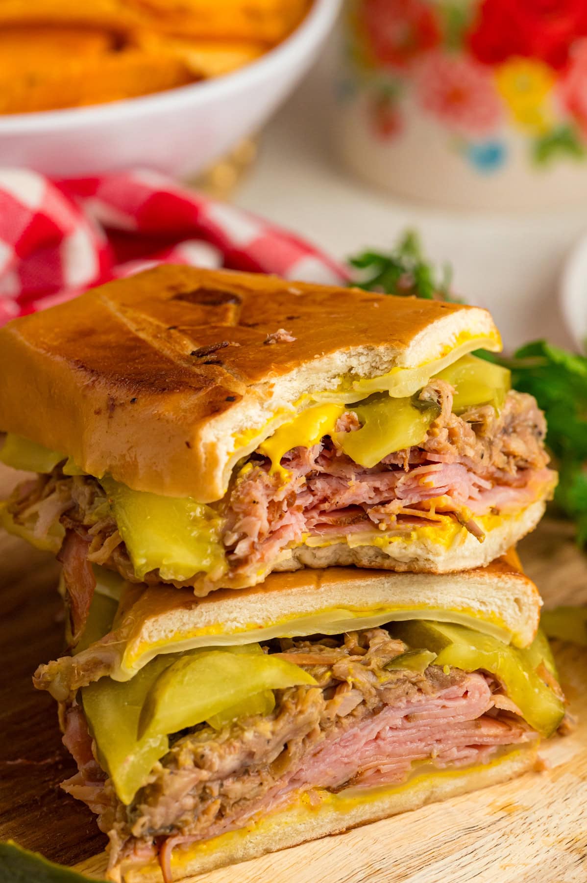This classic Cuban Sandwich recipe features ham, Swiss cheese, pulled pork, mustard, and pickles on a loaf of Cuban bread. Easy lunch idea! Two halves of a Cuban sandwich piled on each other