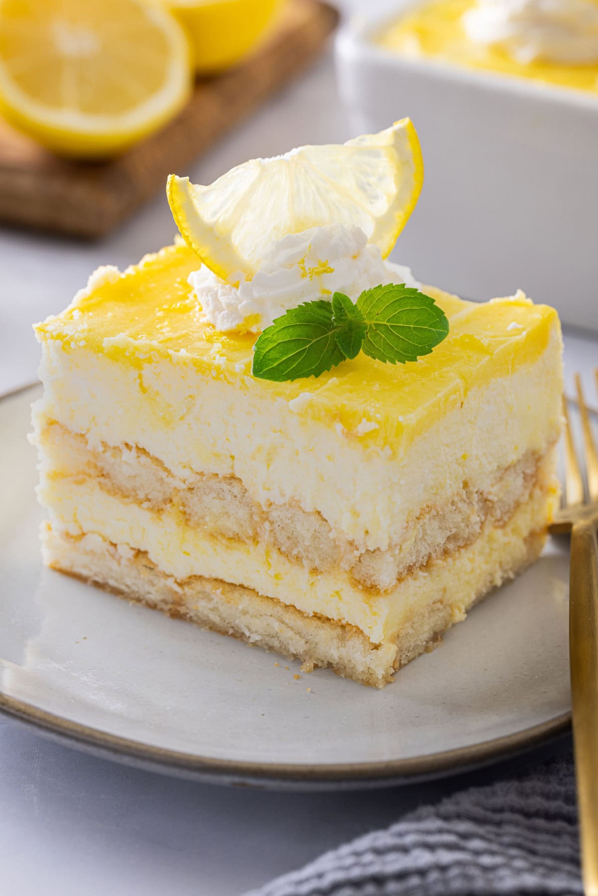 This Lemon Tiramisu is a citrusy, creamy, and delicious take on a classic Italian dessert. If you love classic tiramisu, you are going to love this recipe. A serving of Lemon Tiramisu on a plate with a fork next to it.