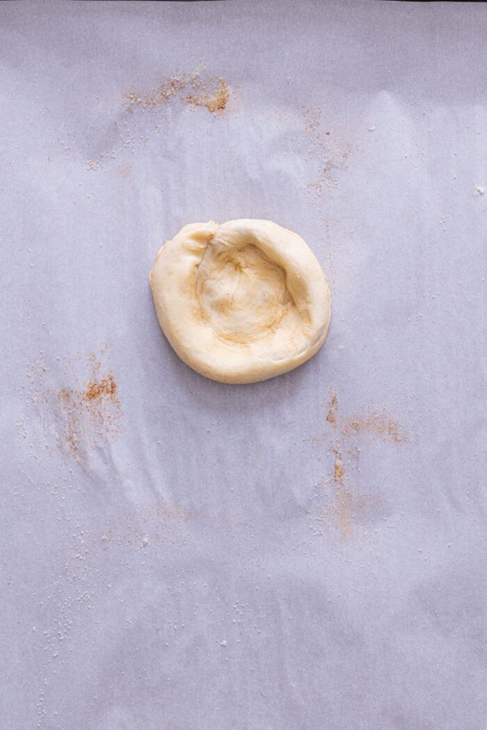 A crescent dough circle with a well pressed into the center
