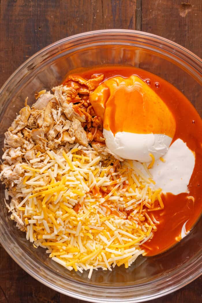 A bowl of shredded chicken, cheese, buffalo sauce, ranch, and cream cheese