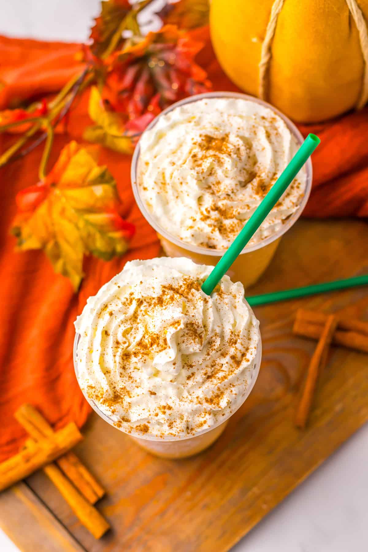 Overhead view of 2 glasses of Pumpkin Spice Frappuccino on a wood serving platter.