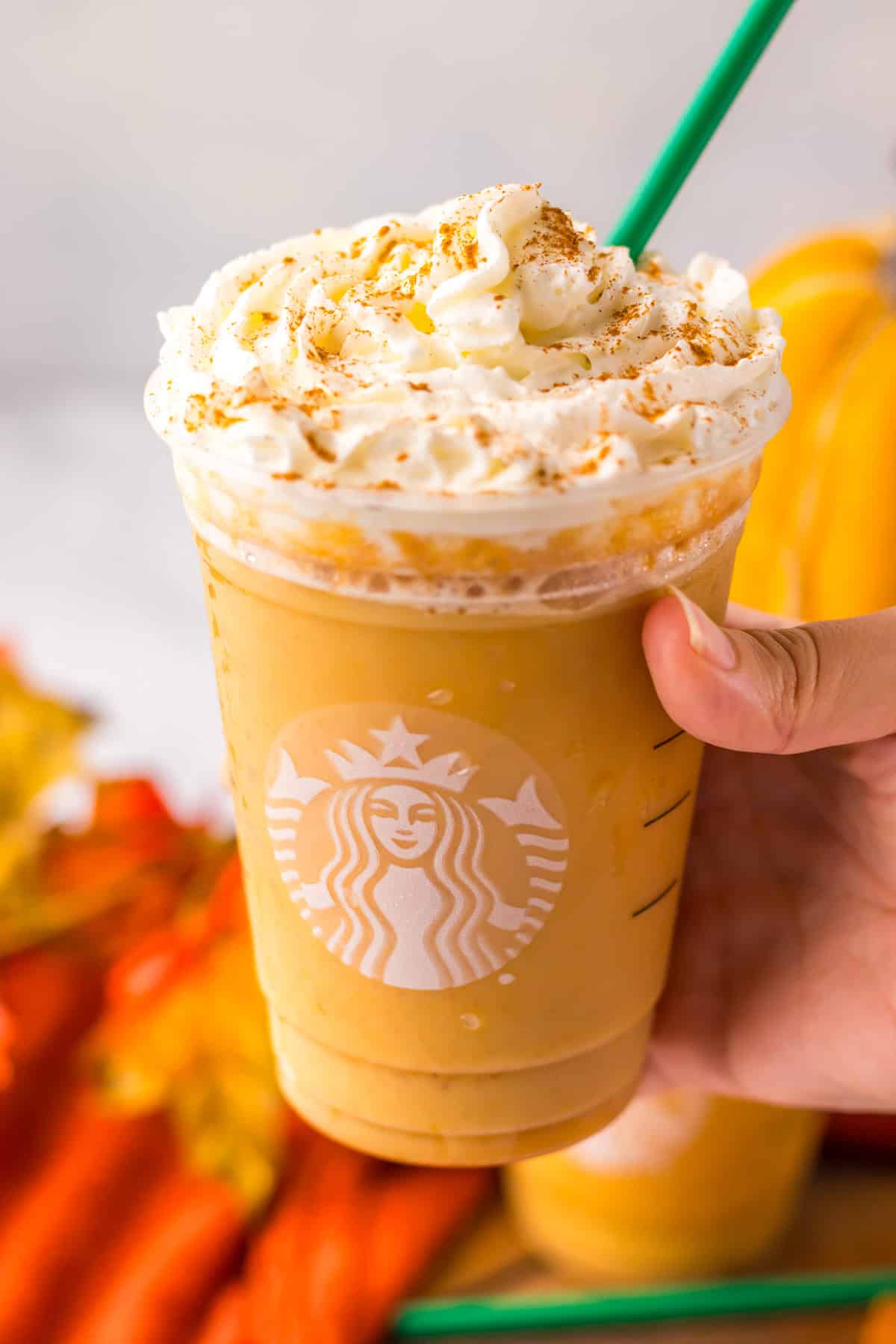 Holding a glass of Pumpkin Spice Frappuccino.