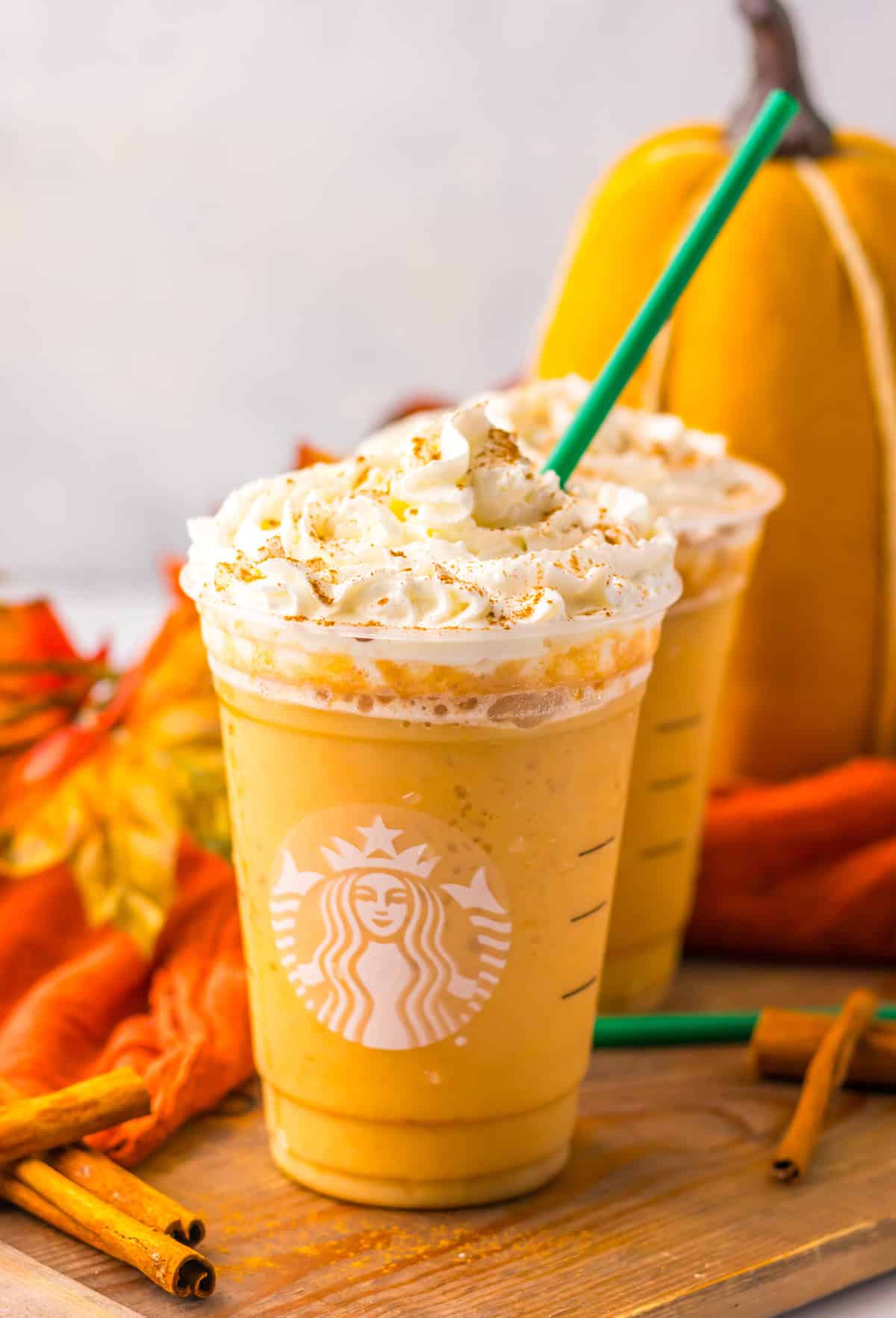 Front view of Two glasses of Pumpkin Spice Frappuccino on a wood serving platter.