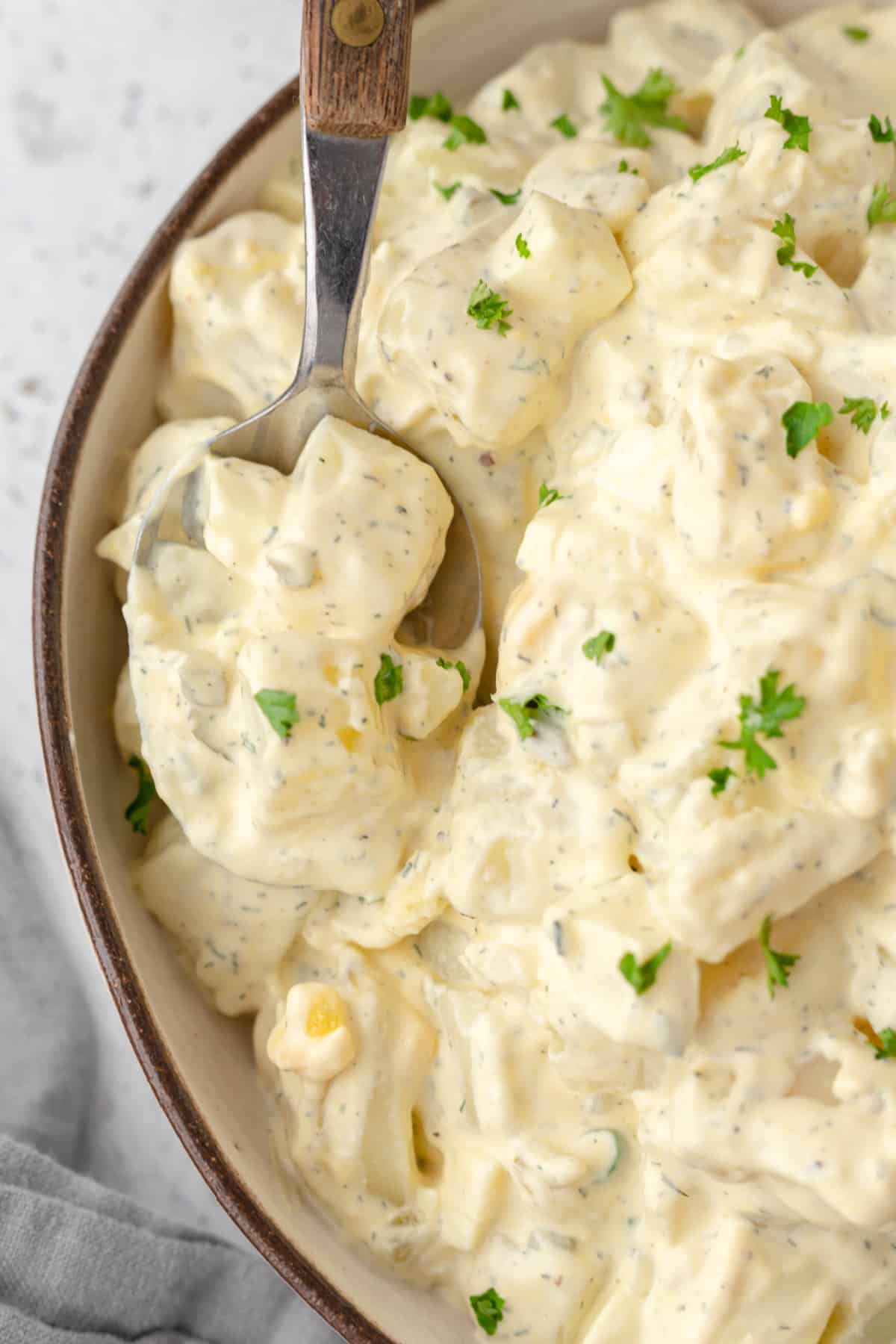 Creamy potato salad in a bowl with a spoon.