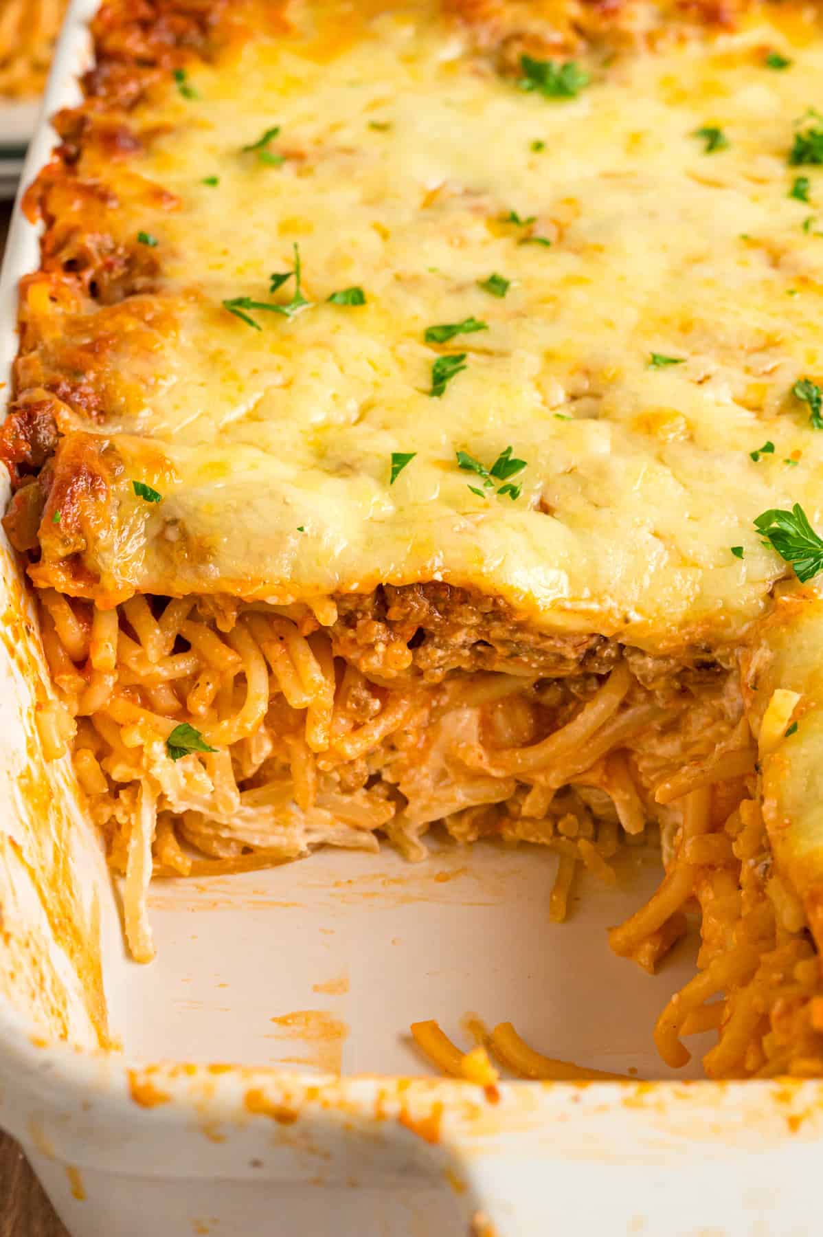 A casserole dish of million dollar spaghetti with a slice missing