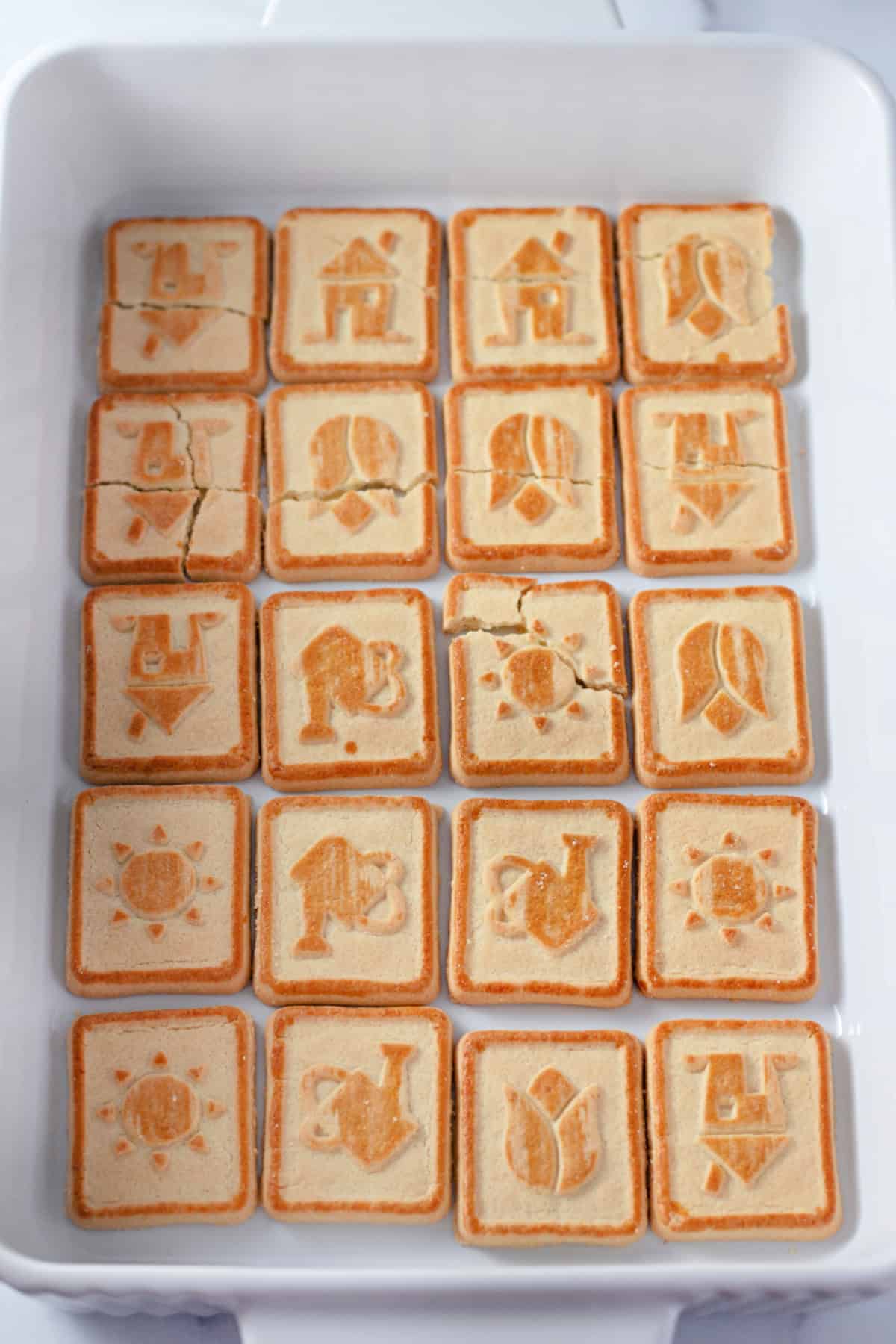 A white rectangular dish with a layer of Chessmen Cookies placed neatly in rows for banana pudding.