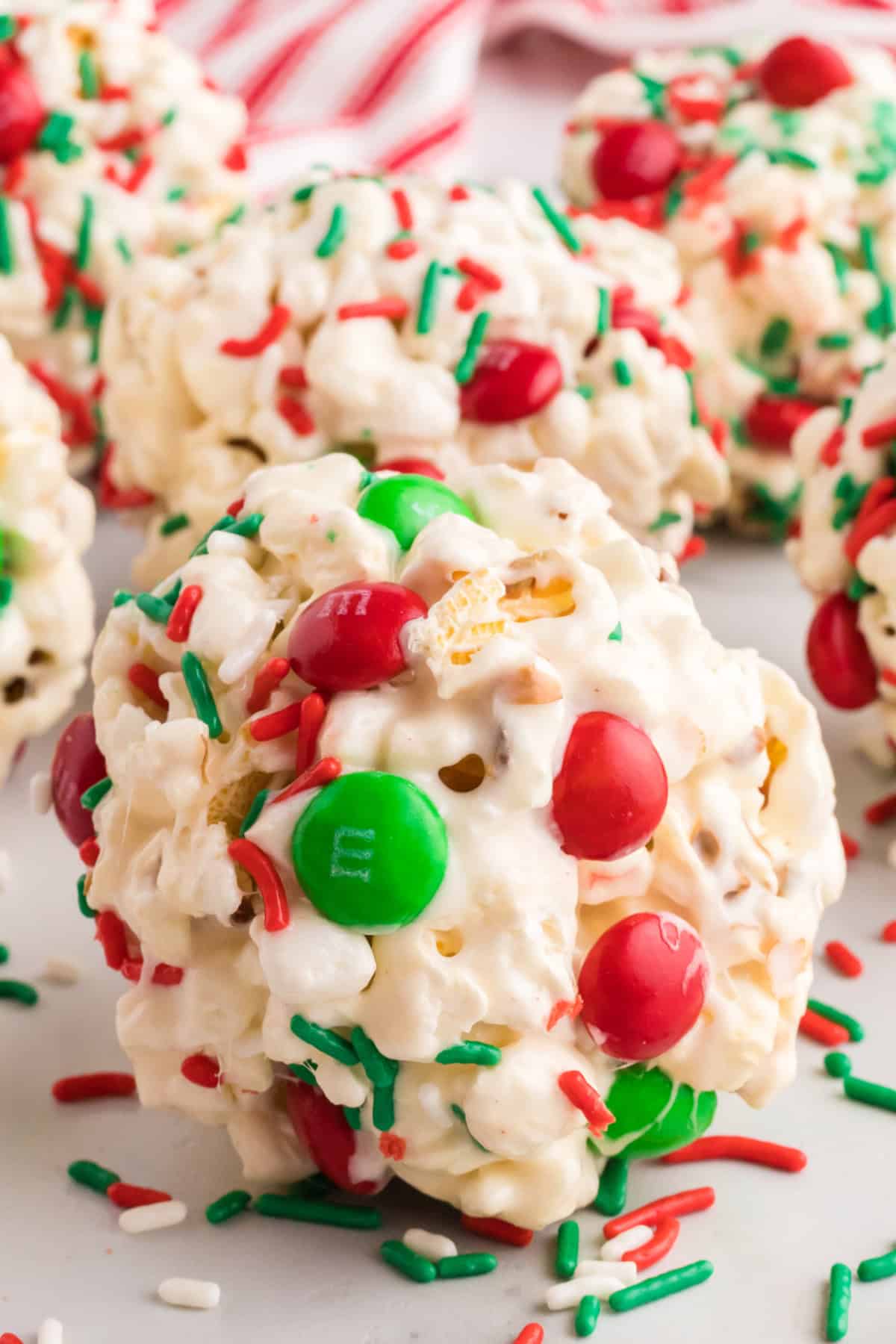 Festive popcorn ball decorated with red and green M&Ms and colorful sprinkles, perfect for the holiday season.