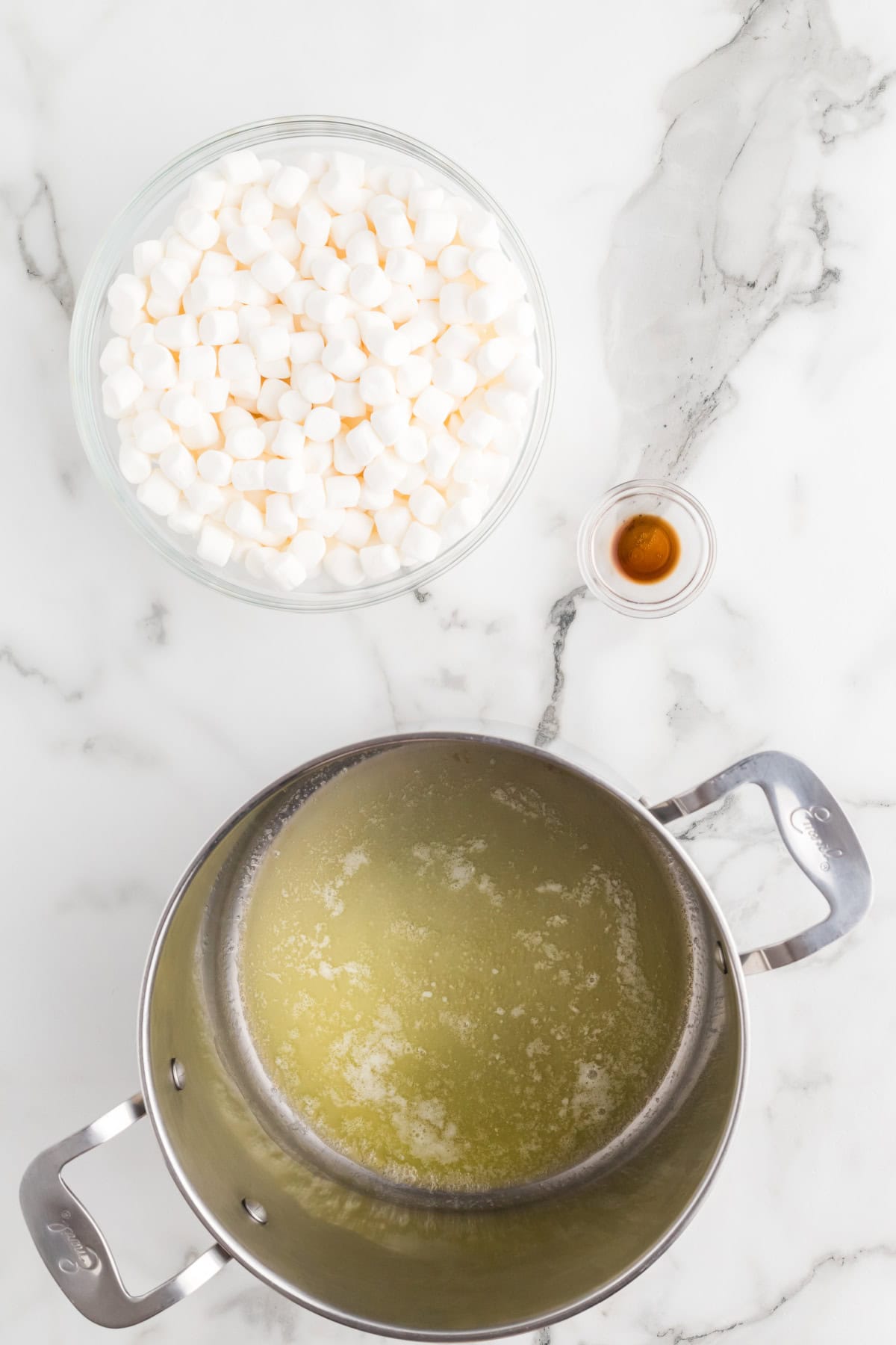 Overhead shot of melted butter in a pot with marshmallows in a bowl beside it, ready to be added for popcorn balls.
