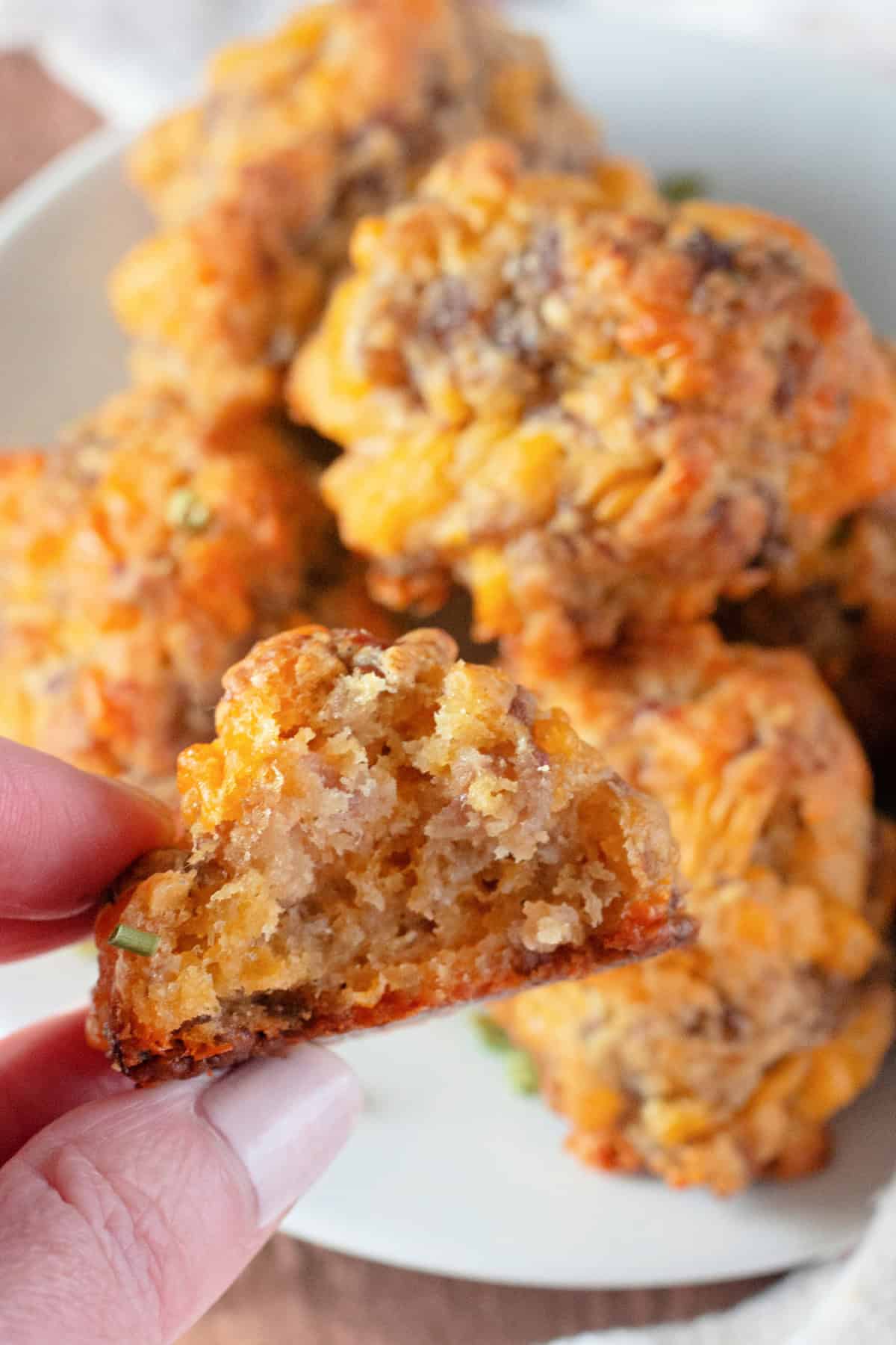 Close-up of a sausage ball with a bite taken out, revealing its soft and cheesy interior.