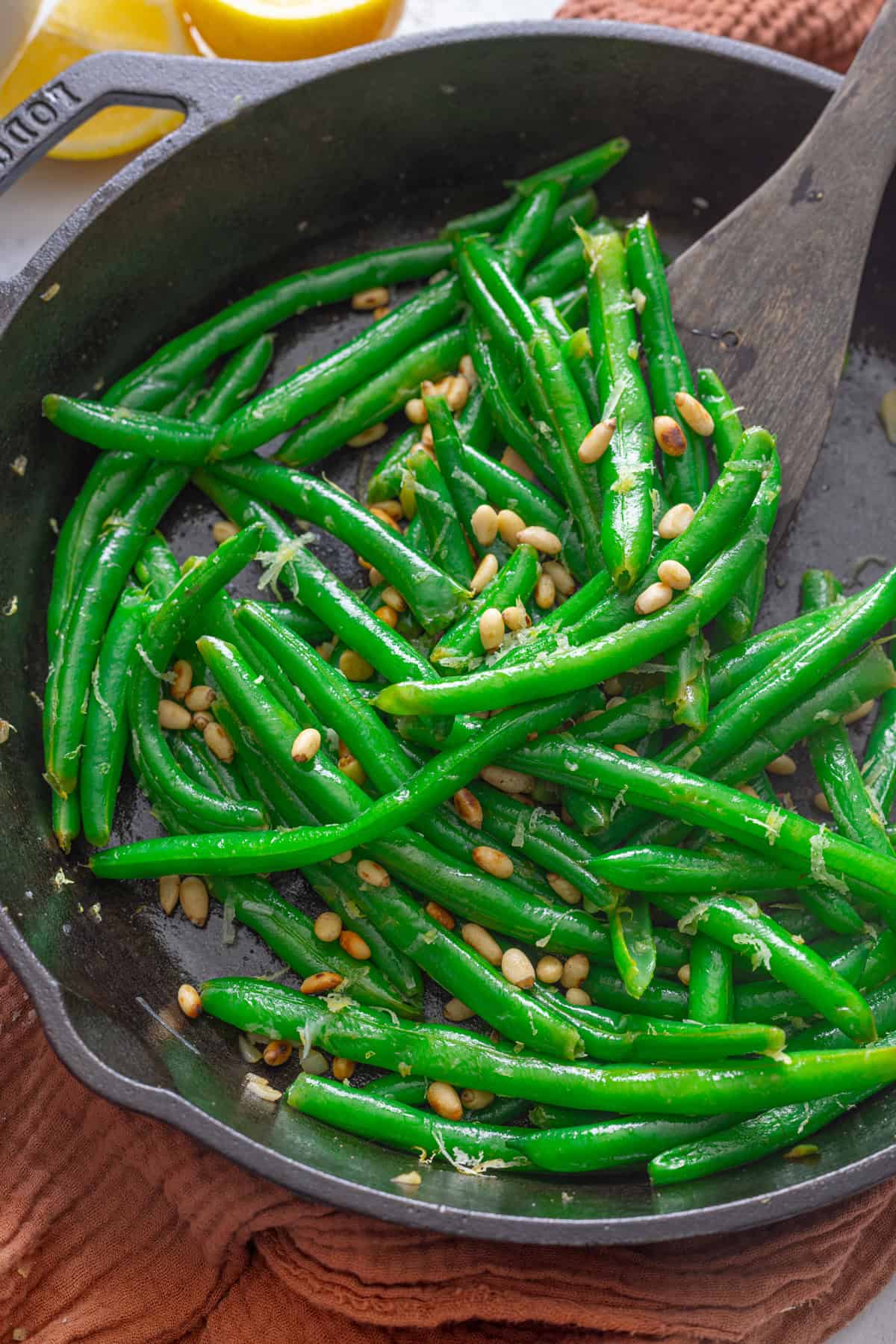 A wooden spoon stirring sauteed green beans